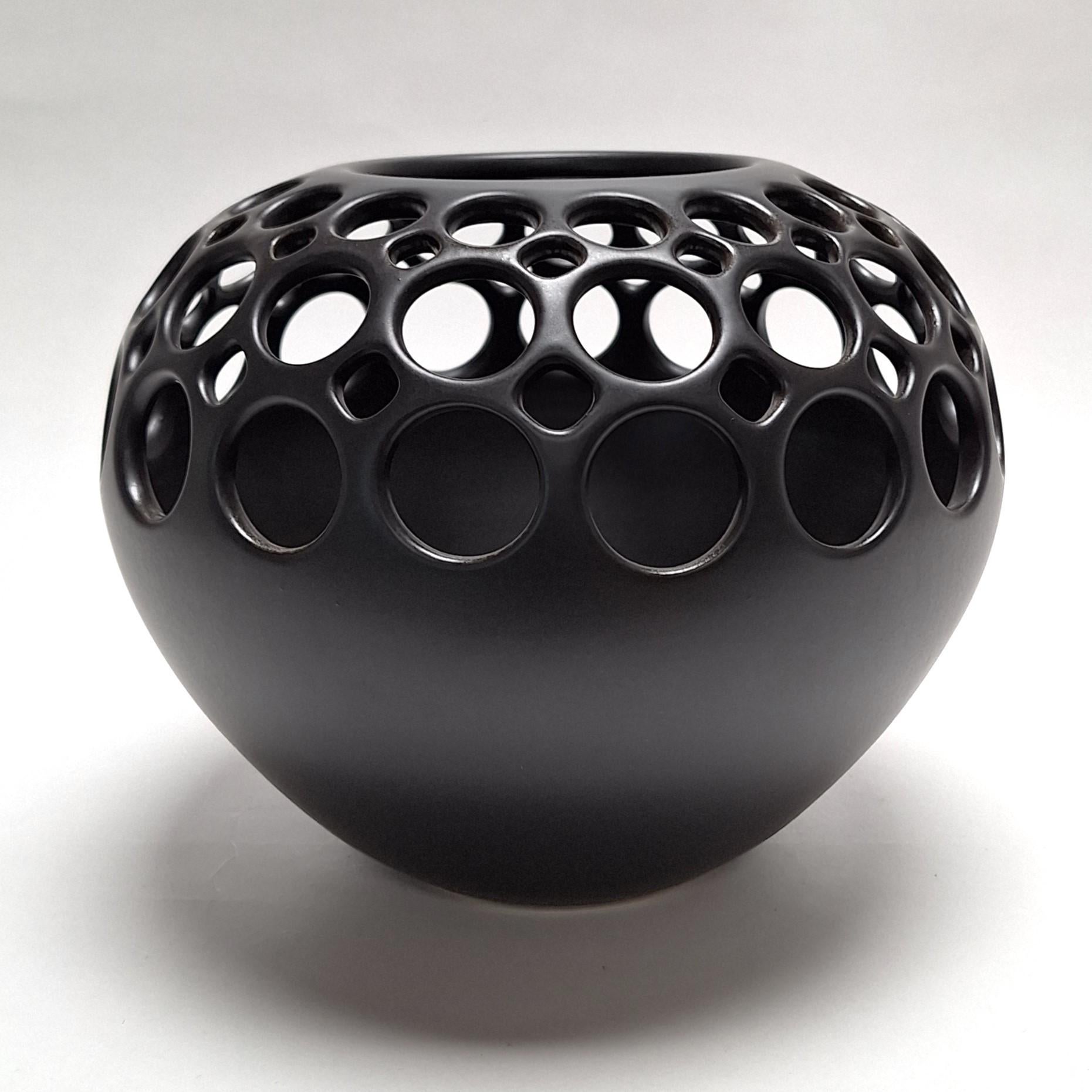 This Orb Demi Round Lace Black Vessel is a unique medium size contemporary modern ceramic object by Californian artist Lynne Meade. It is wheel thrown, hand pierced and has a smooth black satin glaze. Everything is done by eye, without molds or