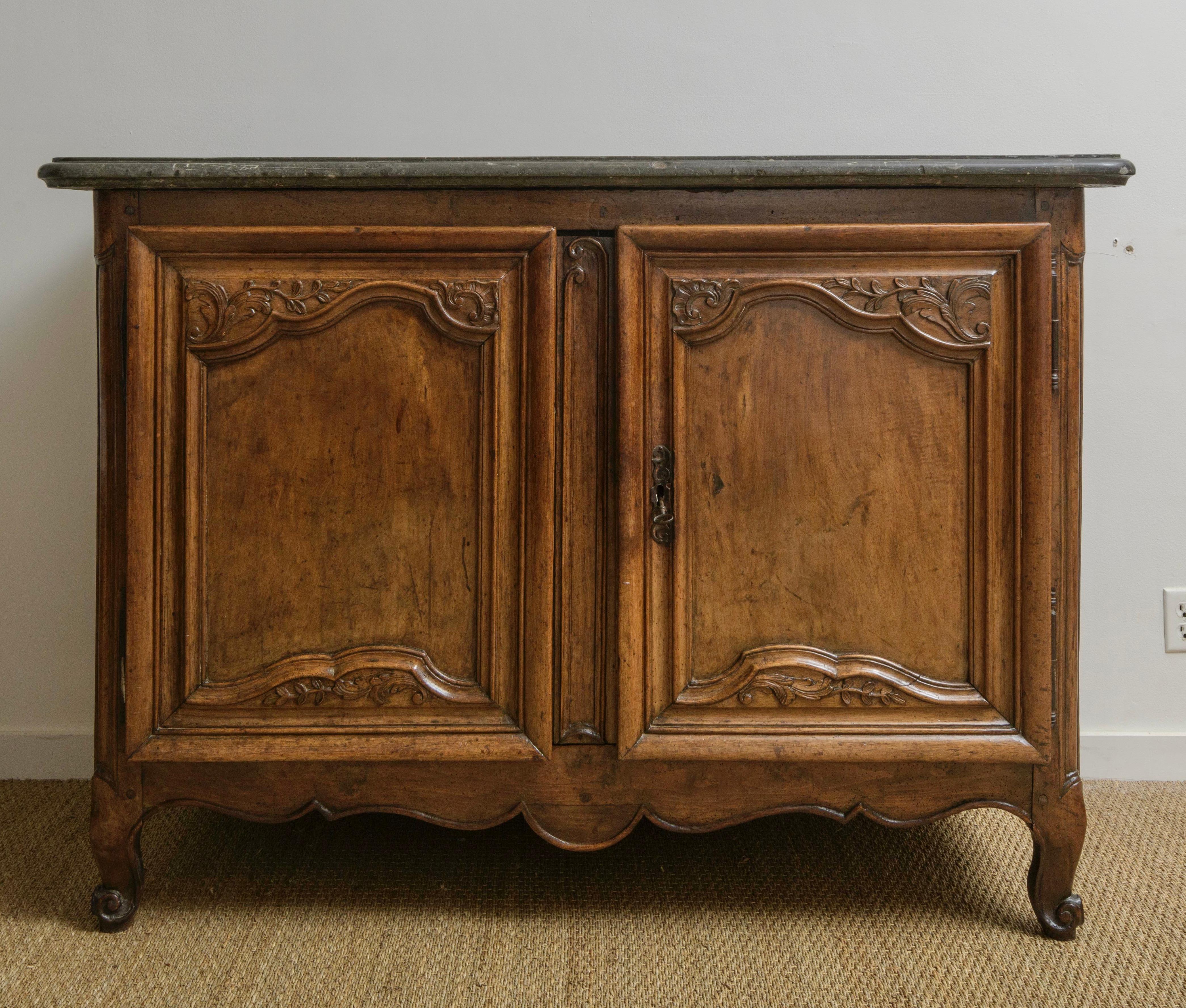From the Louis XV period this exquisite walnut buffet de chasse, ypical of  Lyon region furniture , exudes timeless elegance. Crafted circa 1750 in Lyon, it bears the hallmark of meticulous hand-carving. Crowned with the original  1 7/8 thick dark