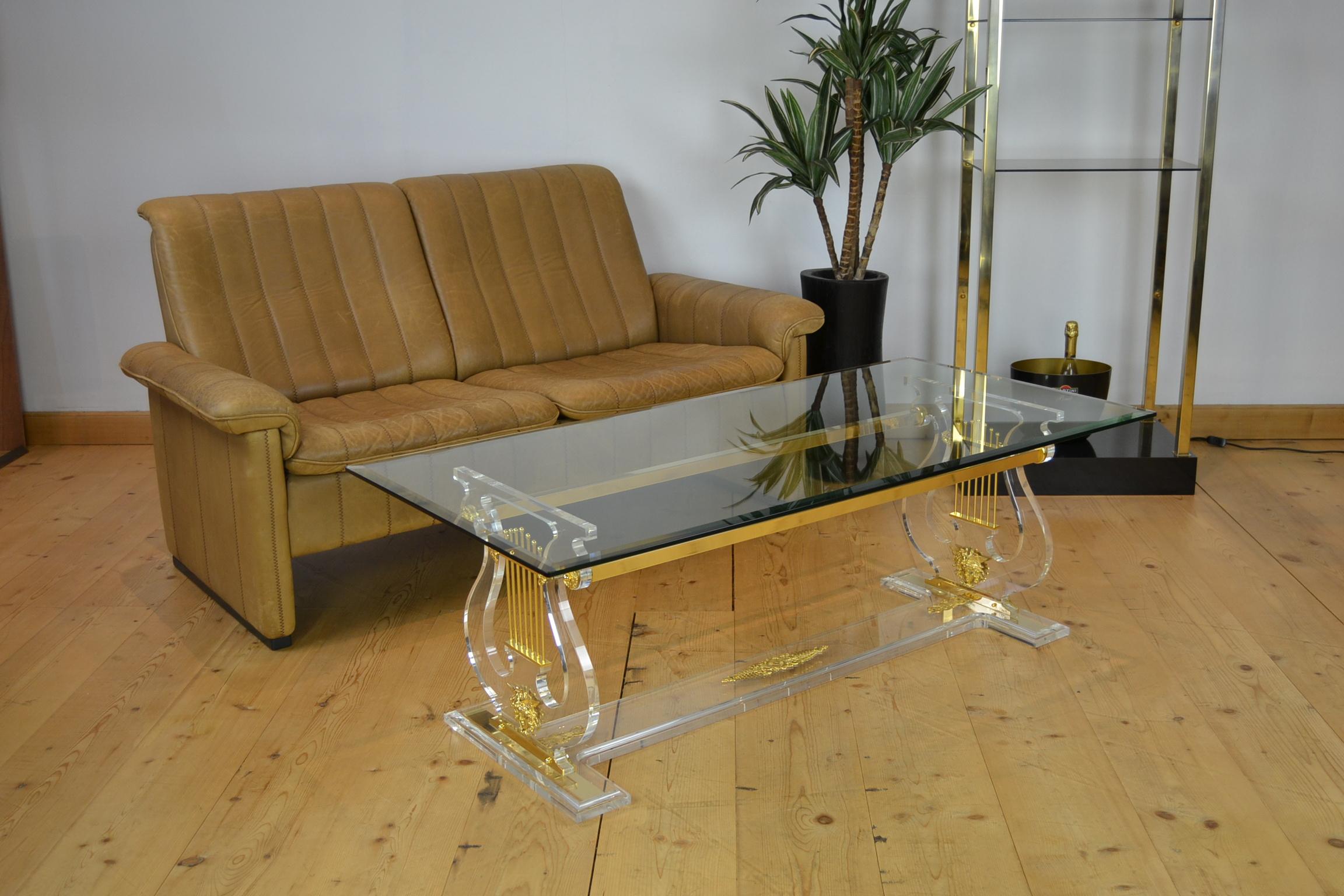 Lyre coffee table or harp coffee table.
This Hollywood Regency table has a Lucite or Plexiglass base
with a thick beveled glass table top which is still in very beautiful condition. 
At the right and left of the table base you see the harp or