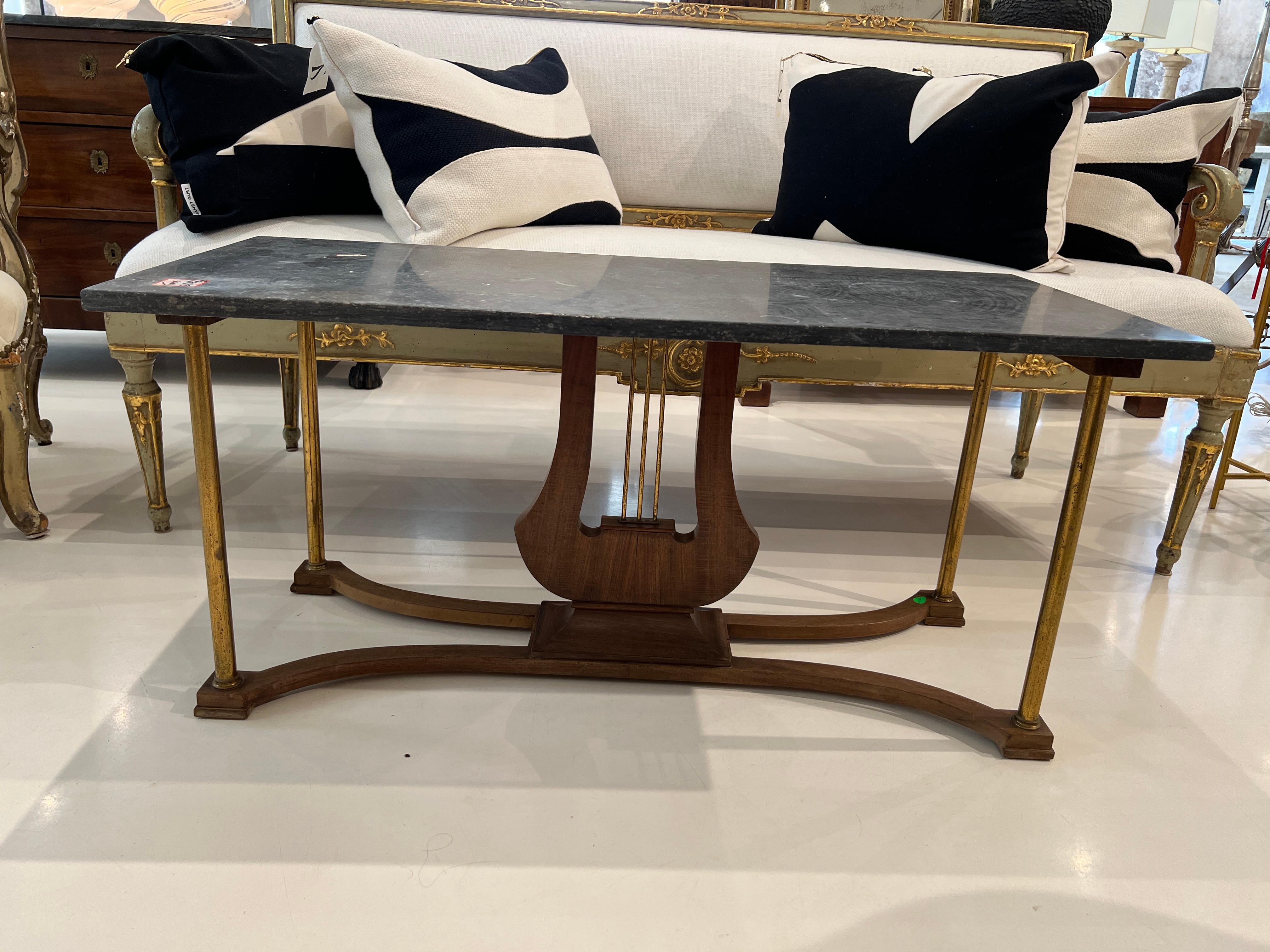 The dark marble top is supported by a lyre shaped base and brass legs. This vintage french coffee table will make a beautiful addition to any seating area. 