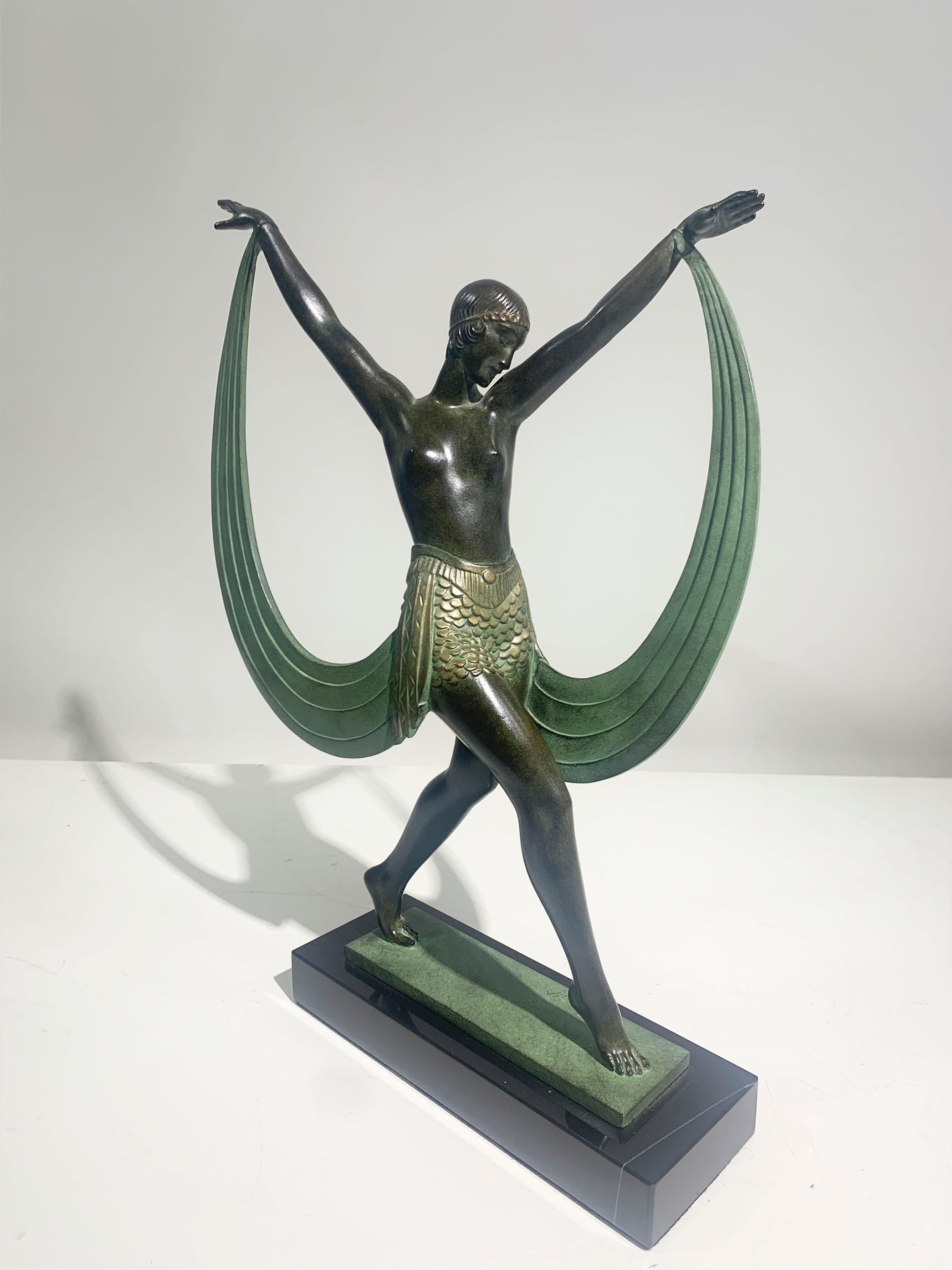 Escultura de bailarina alta Lisis, que representa a una doncella desnuda. Su cintura está cubierta por una falda texturizada con largos drapeados de tela sujetos a sus muñecas. La estatua está montada sobre una base de mármol negro. Firmado Fayral 