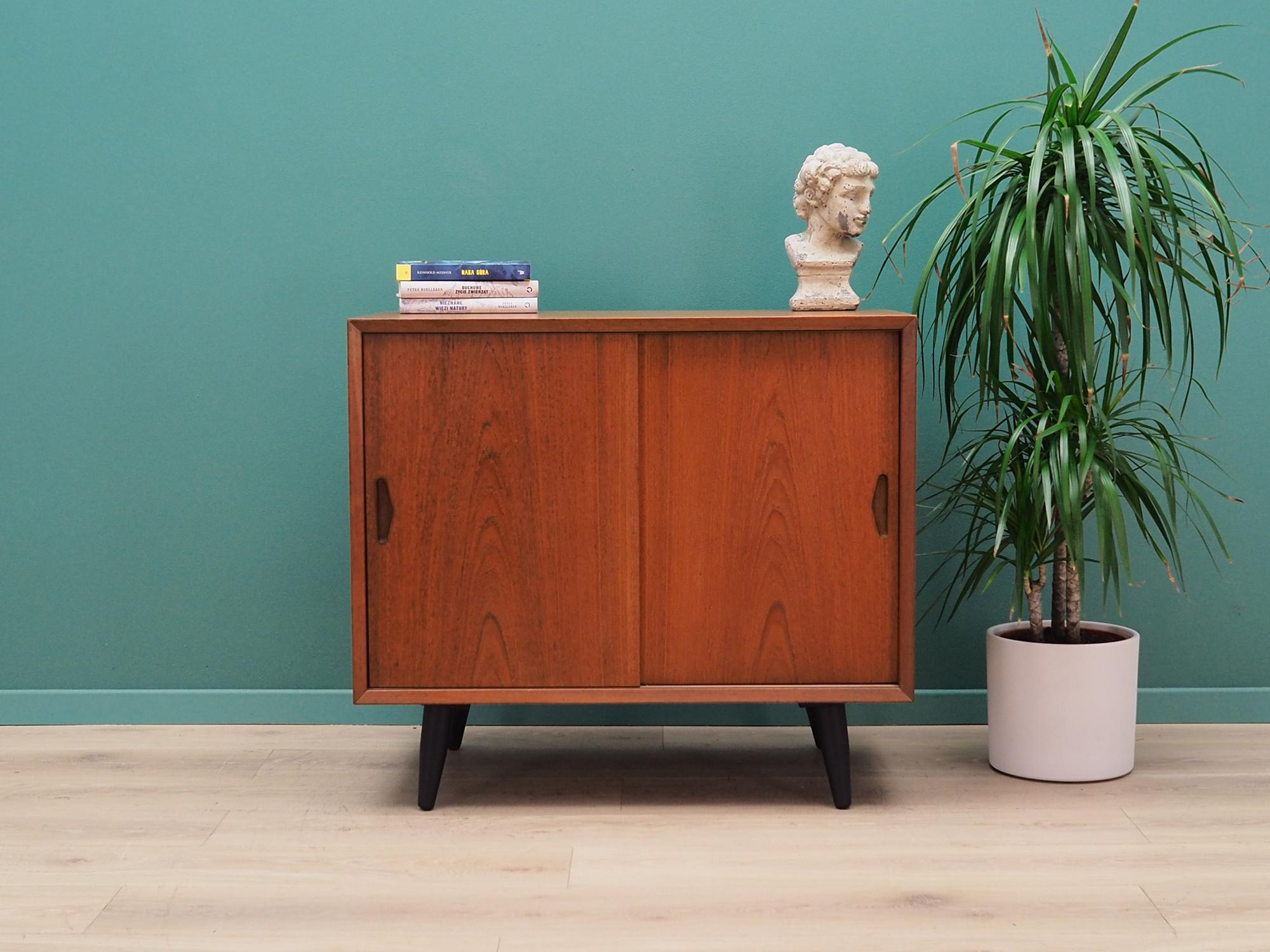 Fantastic cabinet from the 1960s-1970s. Danish design, Minimalist form. Manufactured in Øm Møbelfabrik manufactory. The furniture is covered with teak veneer, legs are made of solid wood. The centre of the furniture is filled with a stylish shelf.