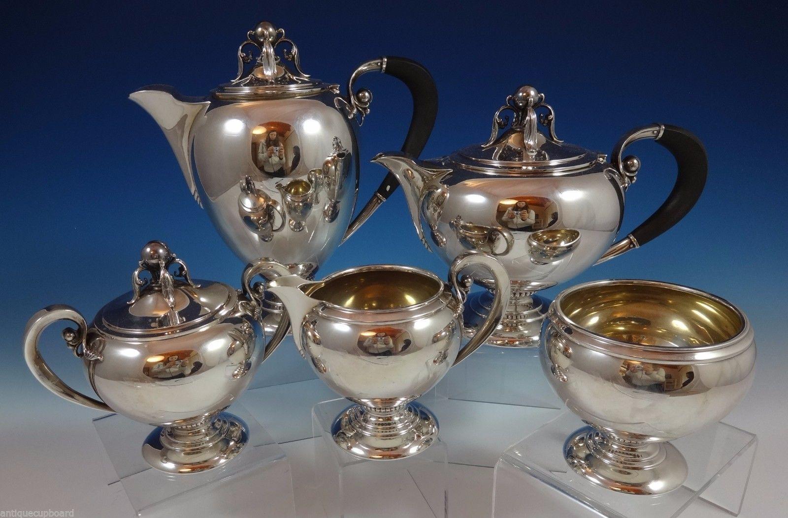 M. Fred Hirsch
Modernism sterling silver 5-piece tea set marked #600 made by M. Fred Hirsch Co. of New Jersey circa 1920-1945. The tea set features 3-D cast ball and leaf elements on the finial and by the ebony handles. The set includes: Coffee pot: