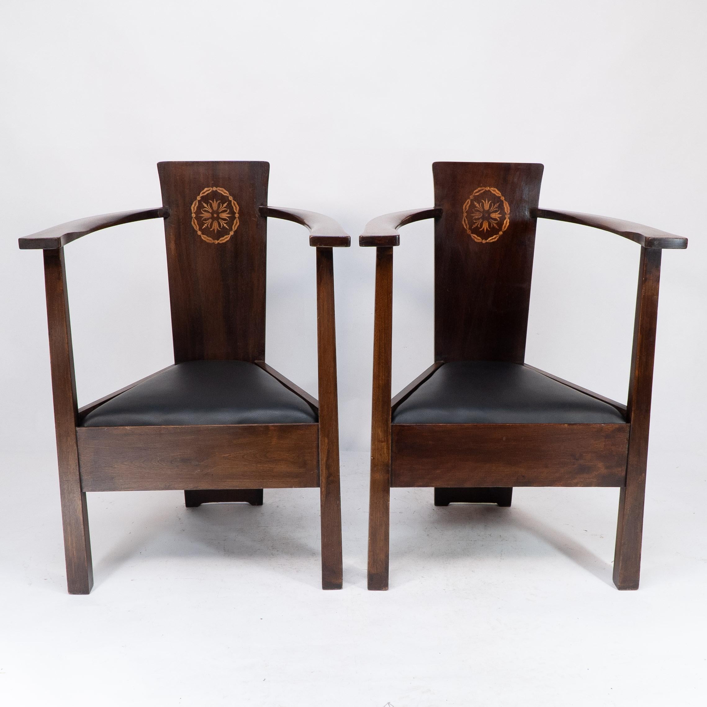 Mackay Hugh Baillie Scott (1865-1945).
A pair of stained beech and inlaid armchairs: The tapering backs forming the main structure of these time less armchairs with foliate and ribbon-bordered roundels, flat curved and shaped arms, triform seats and