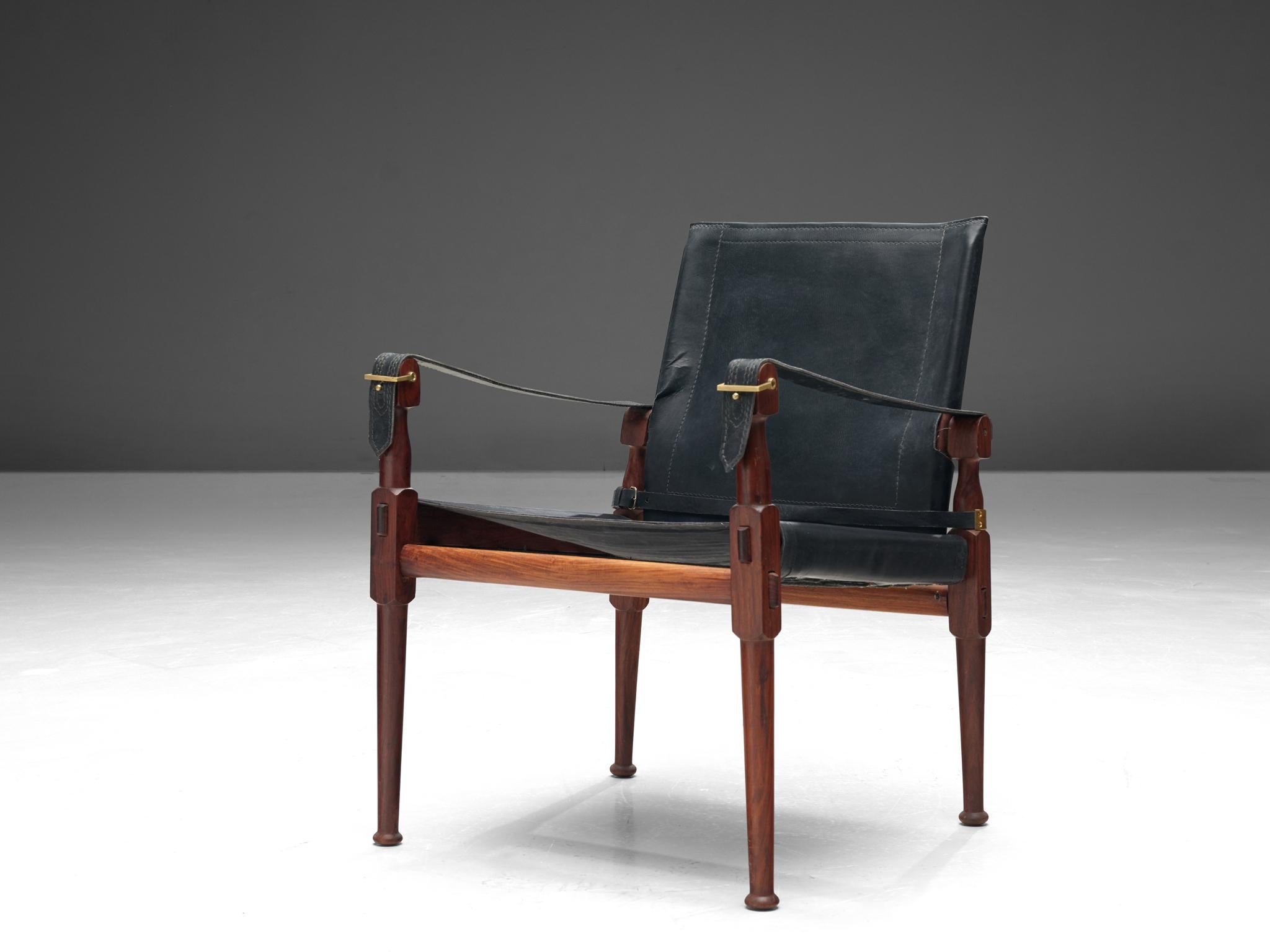 'Safari' lounge chair, wood, black leather and brass, Pakistan, 1970s

This 'Safari' armchair shows very elegant and well designed lines, in combination with carefully crafted wood joints. The black leather with multiple straps completes this
