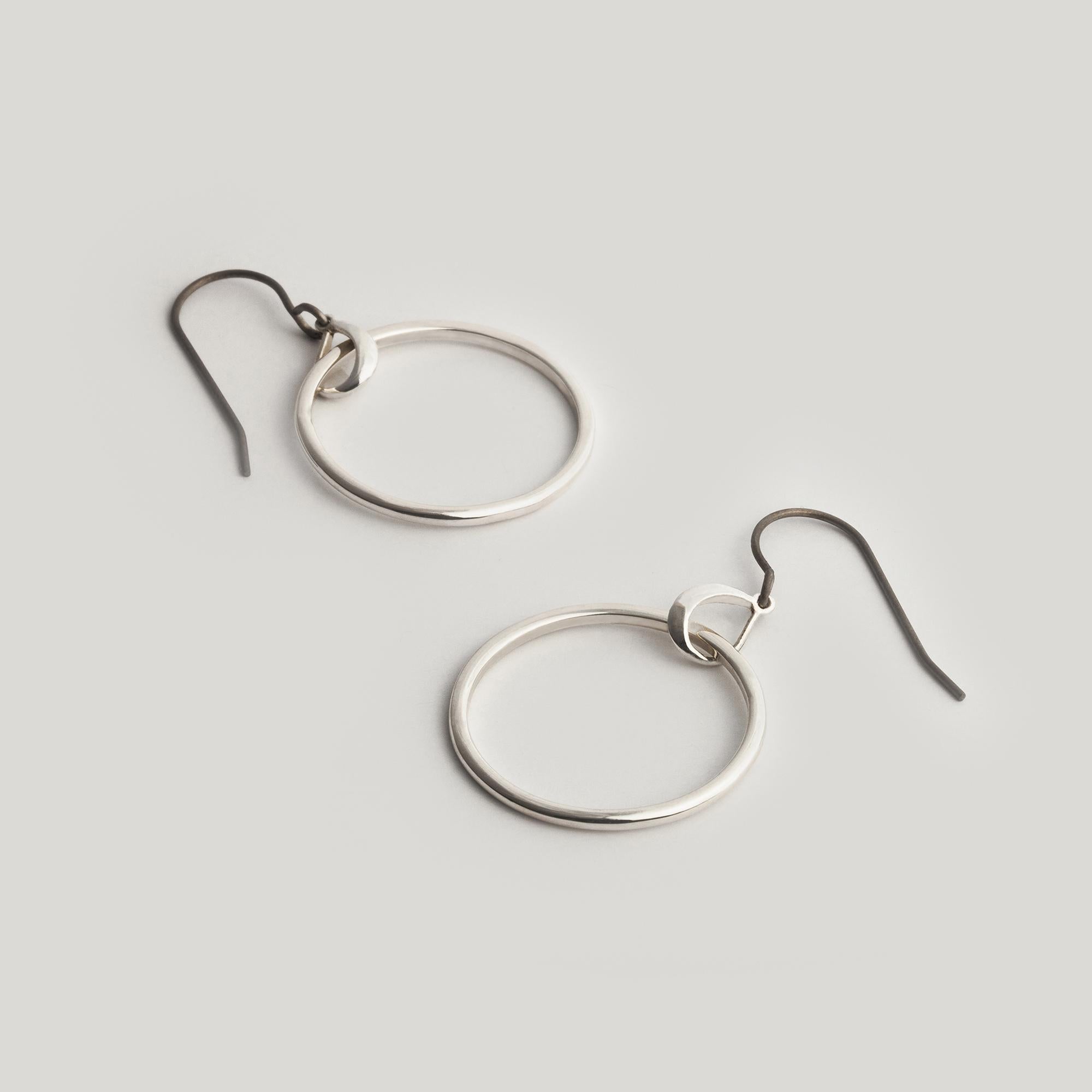 The Austra Hoops play on the concept of orbits, as movement is built into both static and free elements within the design. The suspended hoop is half round wire, half square wire, flowing seamlessly into one another. A dynamic element only seen once