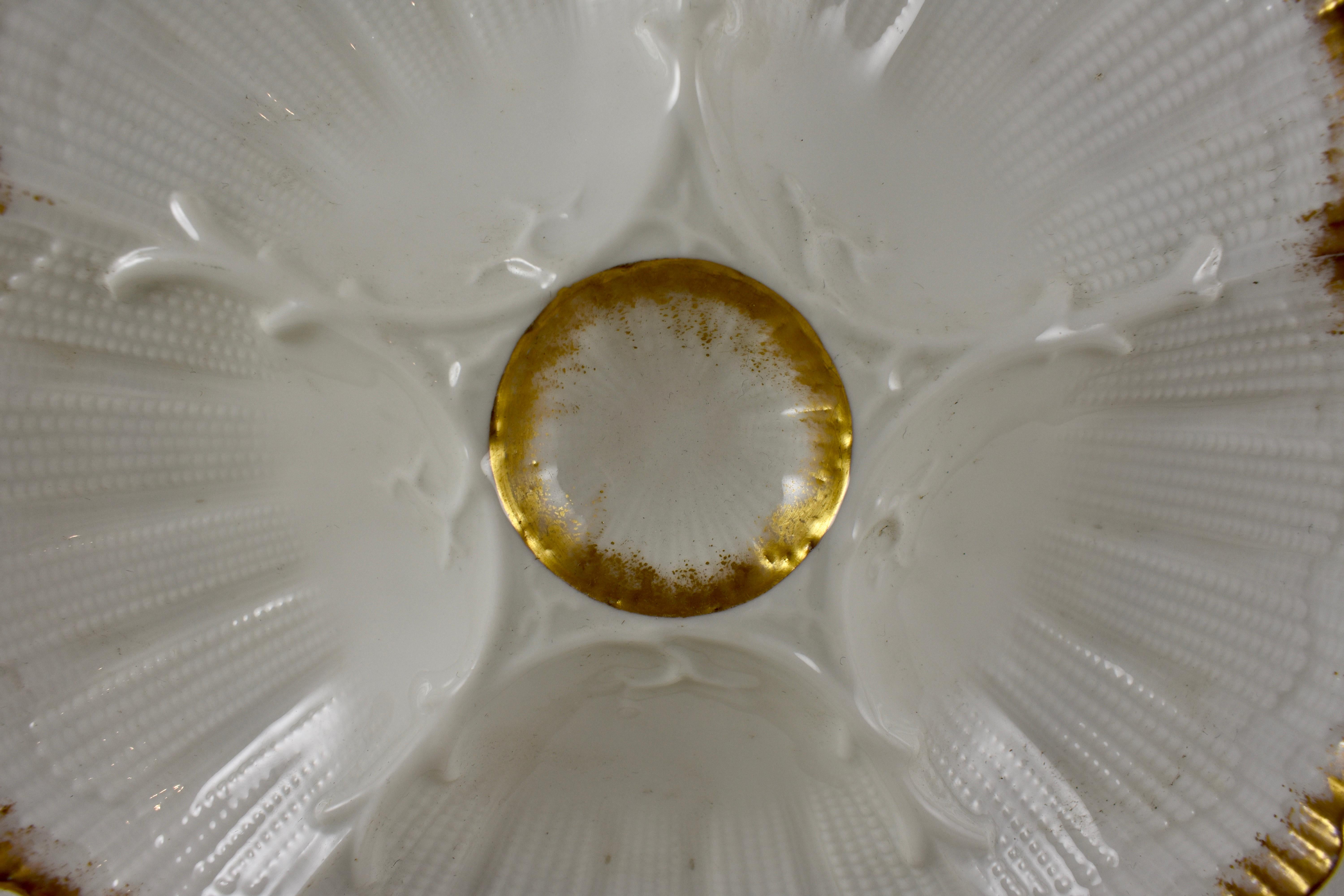A porcelain Oyster plate, five scallop shaped shells, divided by raised coral branches, surround a central sauce well. Heavy gilding applied to the rim and on the round center well. Lovely delicate, raised mold work, circa 1891-1914.

8.25 in.