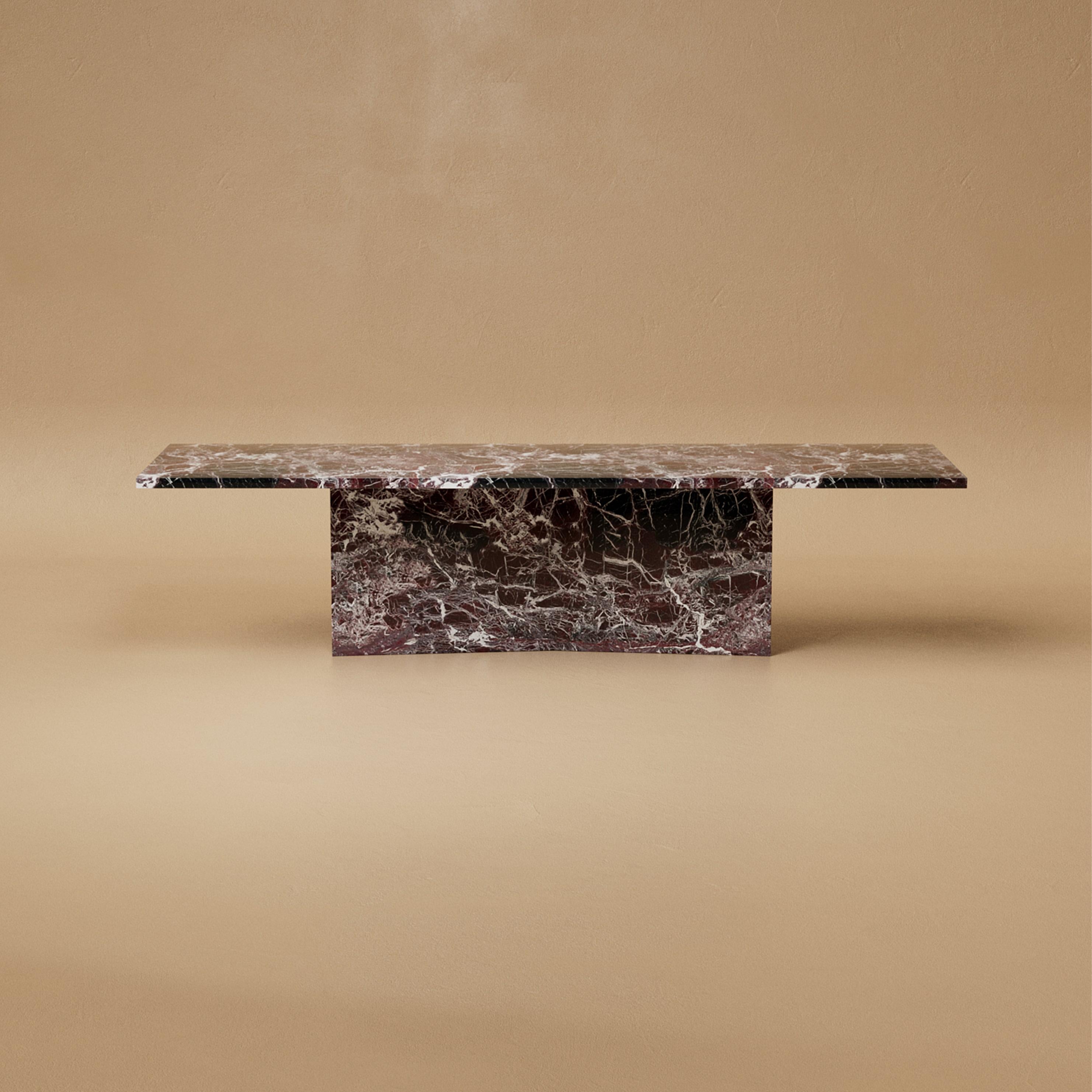 La table de salle à manger Marmont est monolithique mais gracieuse, une présence sculpturale taillée dans la pierre. Sa base en nœud papillon ancre la forme avec une force imposante, tandis que les courbes douces et l'échelle généreuse invitent au