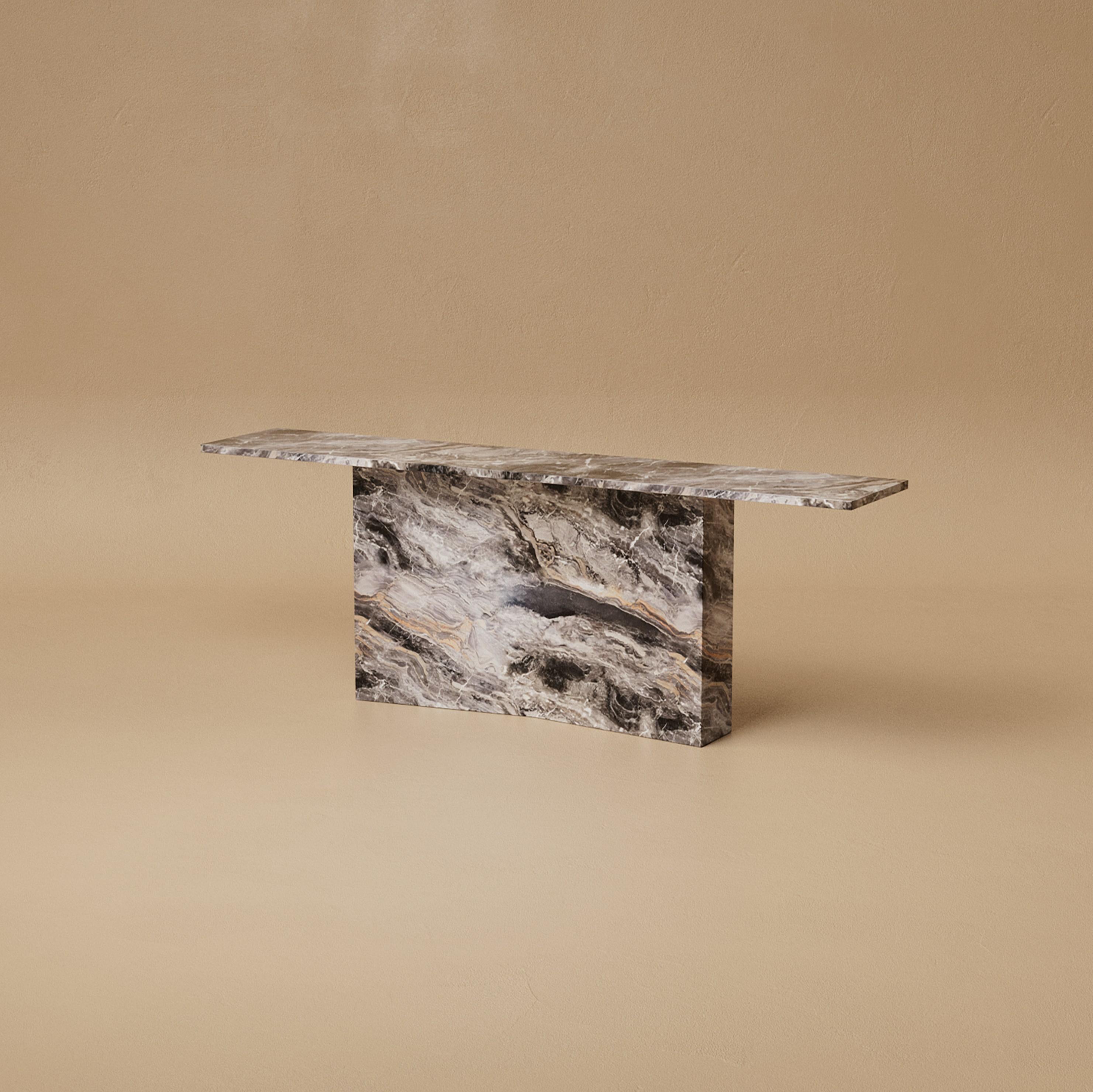 The Marmont Console Table is bold in silhouette yet refined in detail. A bow-tie base, clad in stone, supports a monolithic surface that feels both commanding and elevated. Its geometry is pure and deliberate, creating a sculptural gesture that