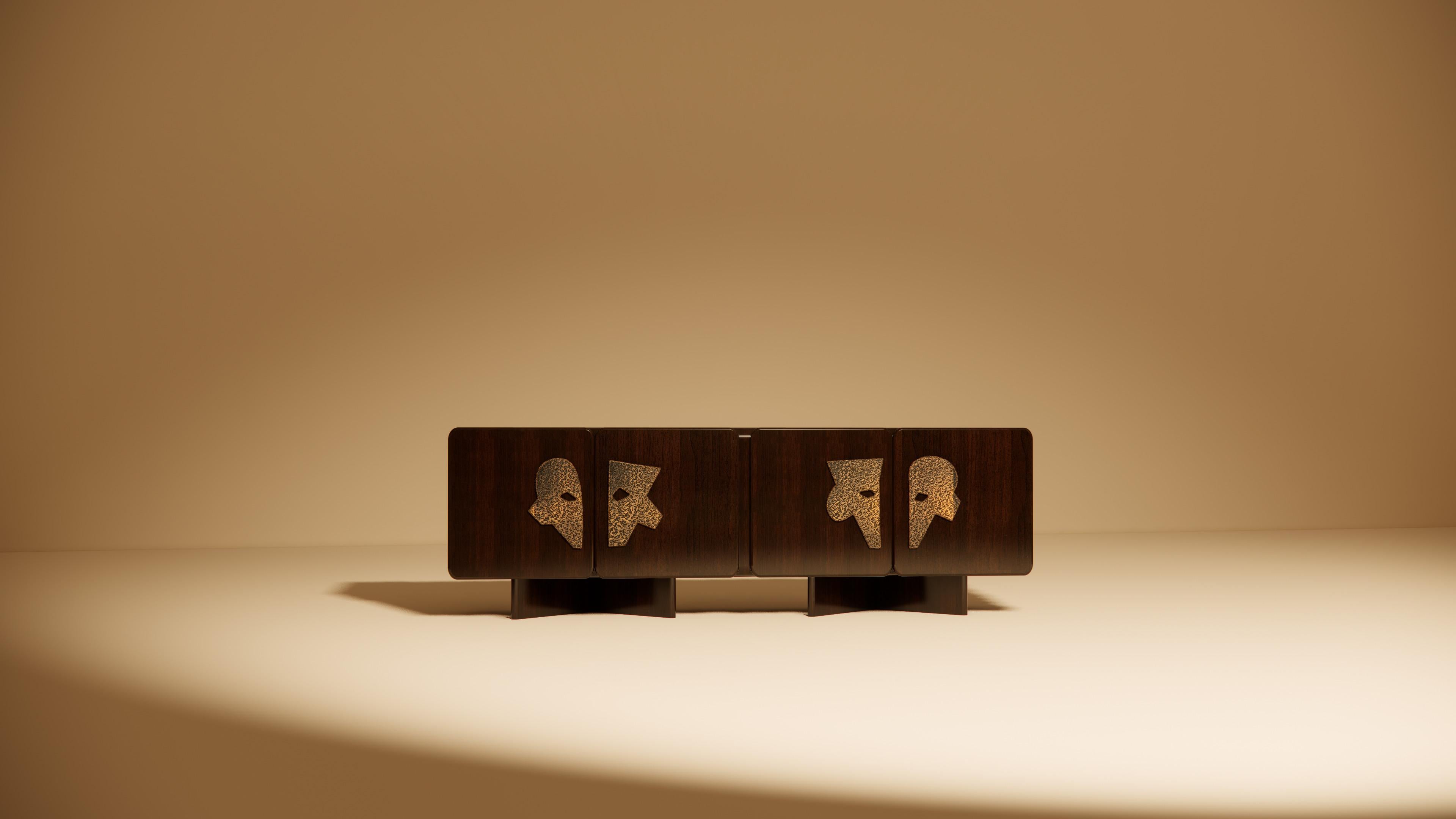 Ma II is a statement credenza that merges functionality with poetic form. Crafted in richly stained walnut, its four doors feature hand-sculpted profiles in hammered brass. These striking brass reliefs evoke ancestral masks or ceremonial emblems,