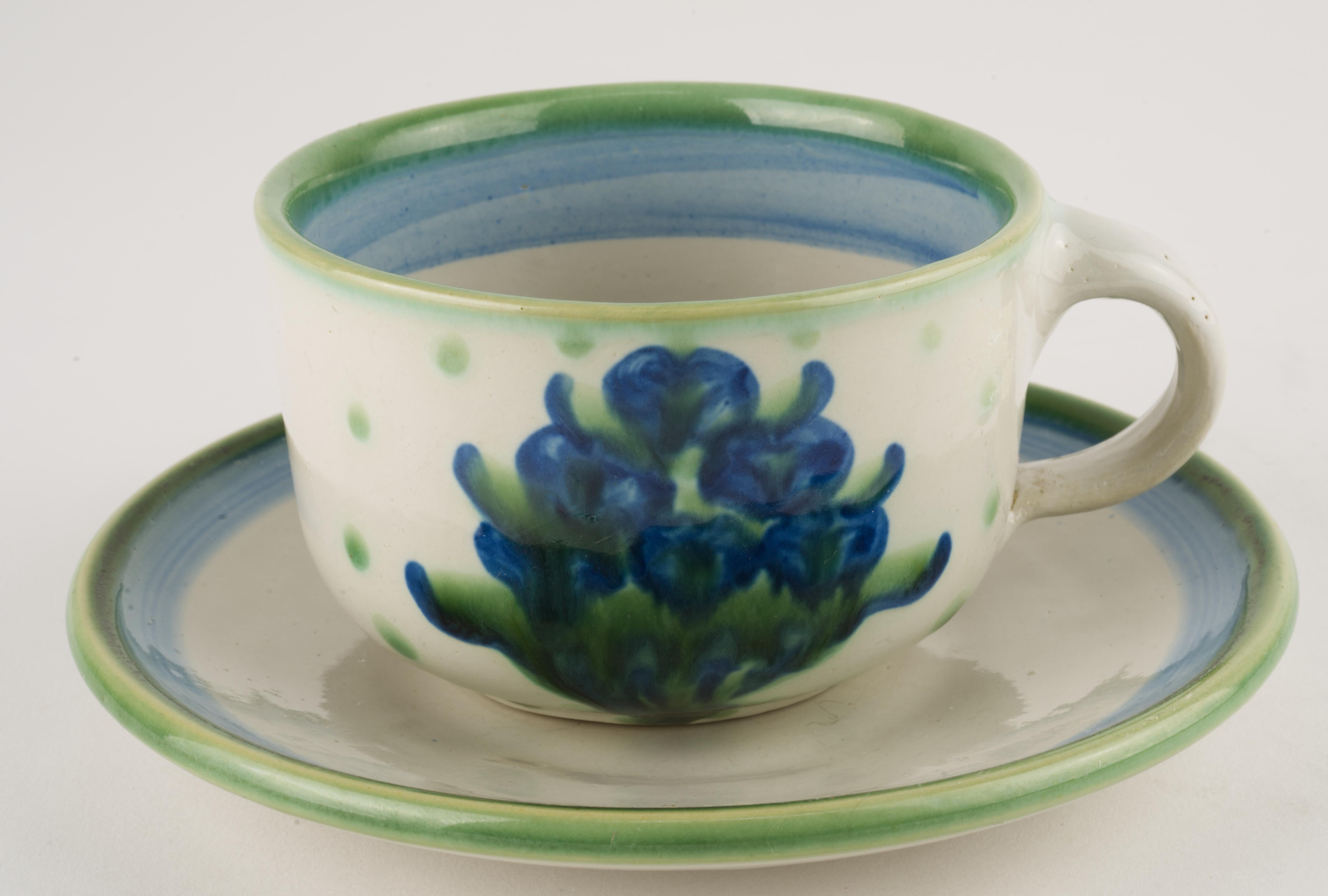  Cup and saucer were thrown and hand painted by Hadley Pottery in Louisville, Kentucky, in Bouquet pattern. The pattern consists of a stylized basket with blue dots/flowers (sometimes referred to as blueberries) surrounded by green dots. Pieces are