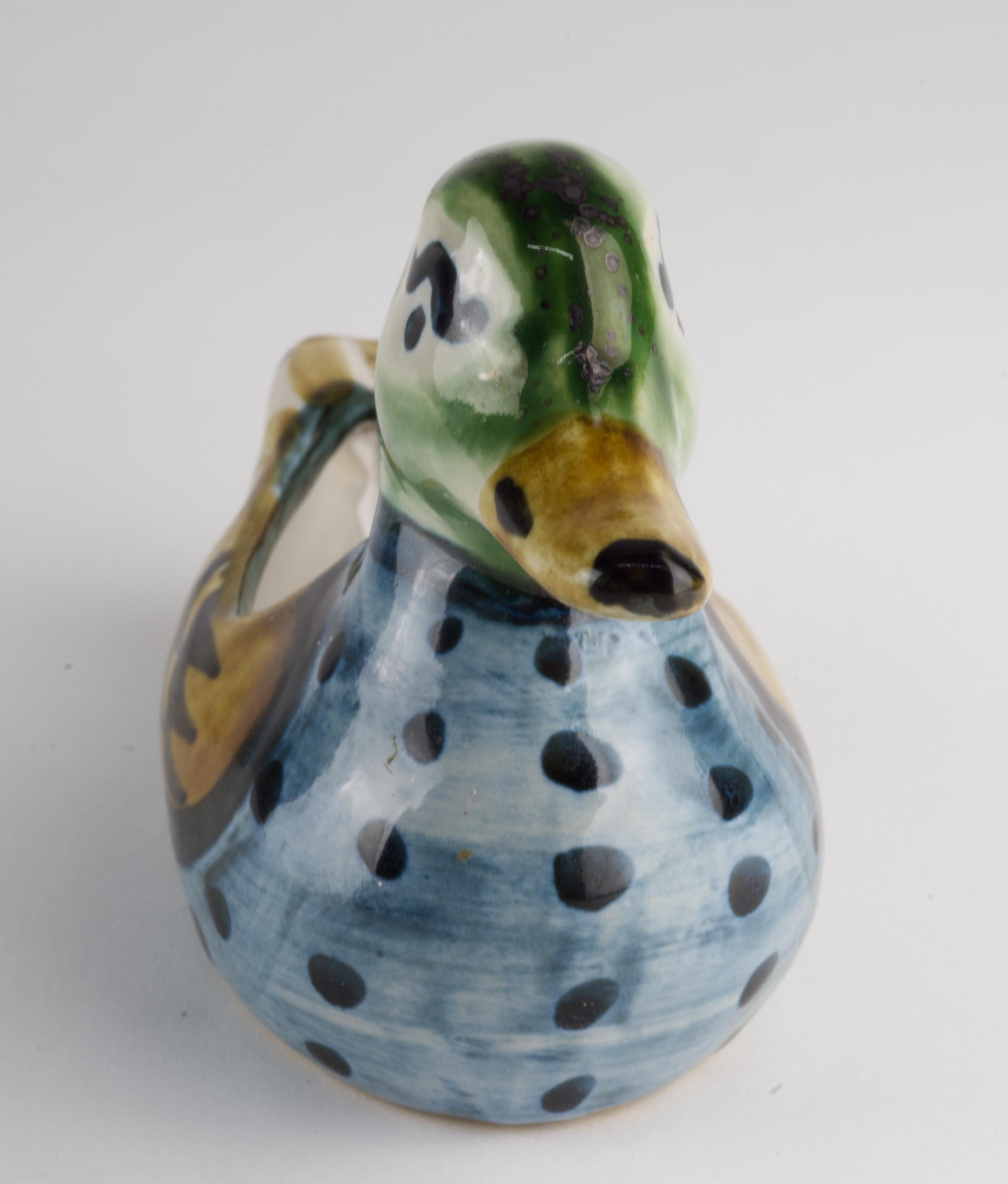  Duck shaped ashtray or catchall was handmade by Hadley Pottery in Louisville, Kentucky. The figurine is hand painted in green, blue, and yellow palette with anthropomorphic eyes that give it playful, endearing expression. The inside of ash