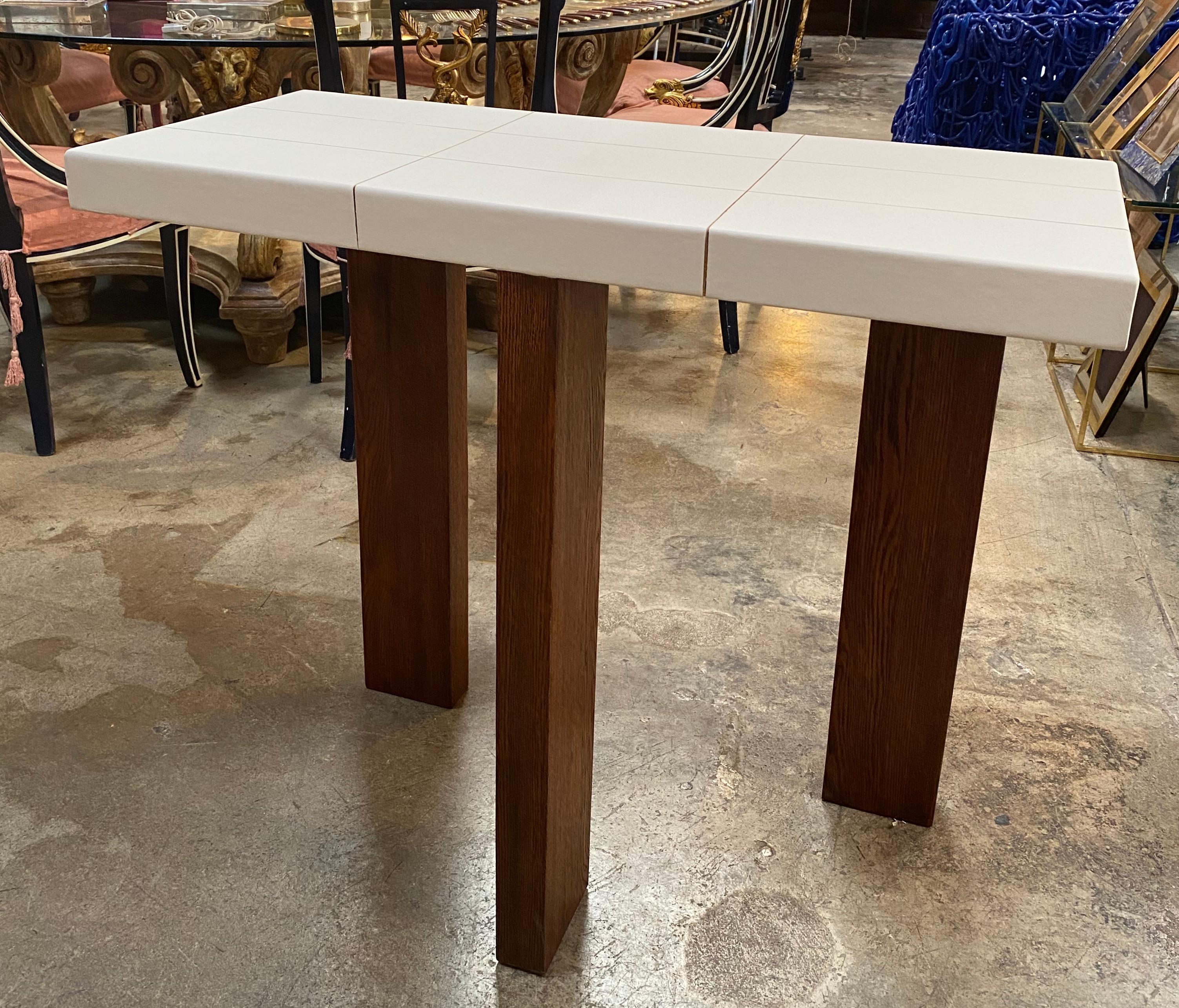 An elegant and sober Italian 21st century modern neoclassical three-legged tables from Italy. The structure is composed of solid walnut wood with an rectangular top gently with parchment base cantilevered over an rectangular apron which rests on