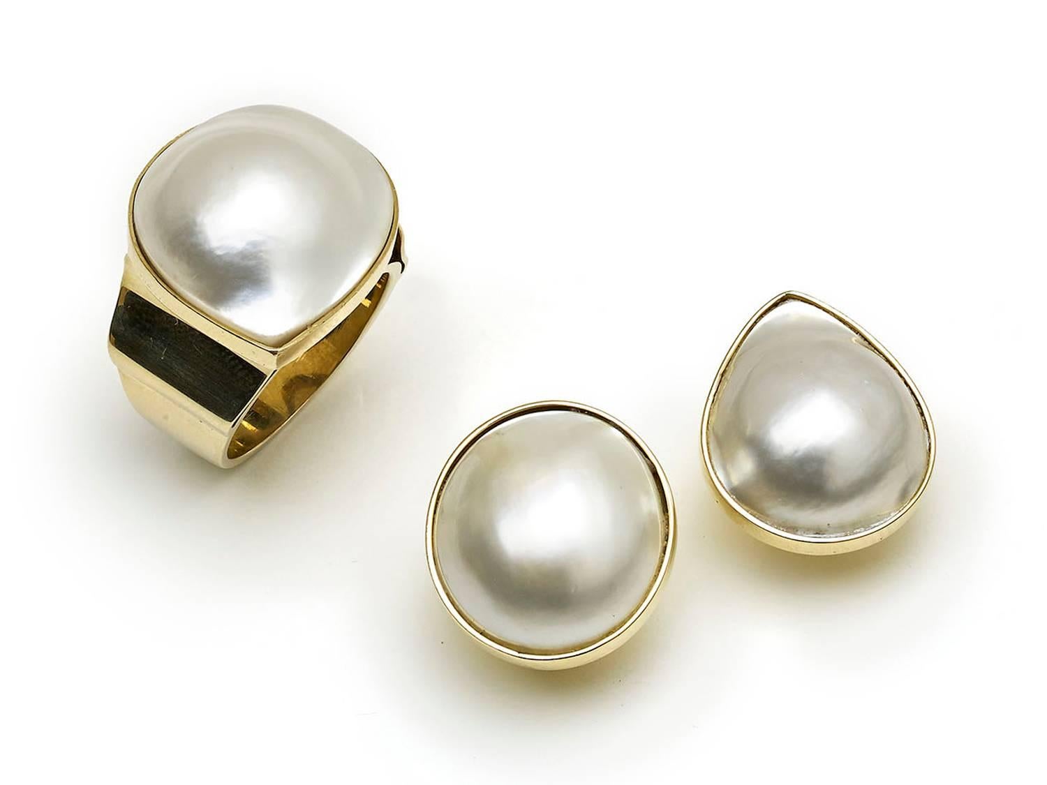 A mabé pearl and gold earrings and ring suite, with a ring, set with a pear shape mabé pearl, in a rub over setting, on a wide, tapering, shank, mounted in 14ct gold, stamped 14K and a pair of earrings, set with one oval and one round mabé pearl, in