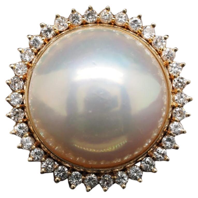 Verleihen Sie Ihrem Look Eleganz mit diesem atemberaubenden Ring aus 14 Karat Gelbgold. Die 16 mm große Mabe-Perle ist mit einem runden Diamanten besetzt, der dem Schmuckstück einen Hauch von Glanz verleiht. Die Breite des Bandes beträgt 3 mm, und