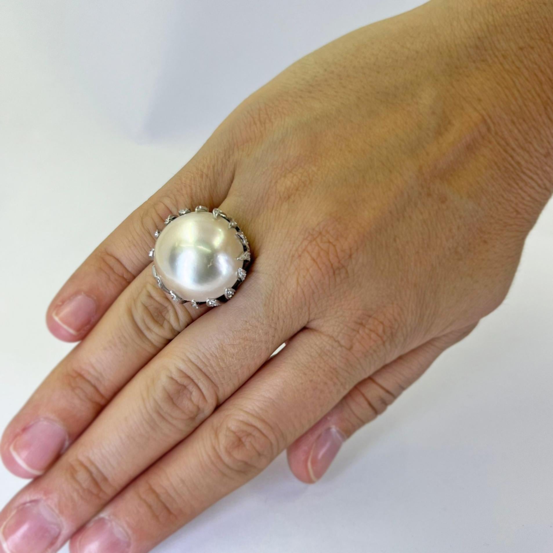 14 karat white gold flame ring featuring a 20mm round Mabe pearl accented by 82 single cut diamonds of VS clarity and G color totaling approximately 2.00 carats. Finger size 6.25. Finished weight is 11.0 grams.