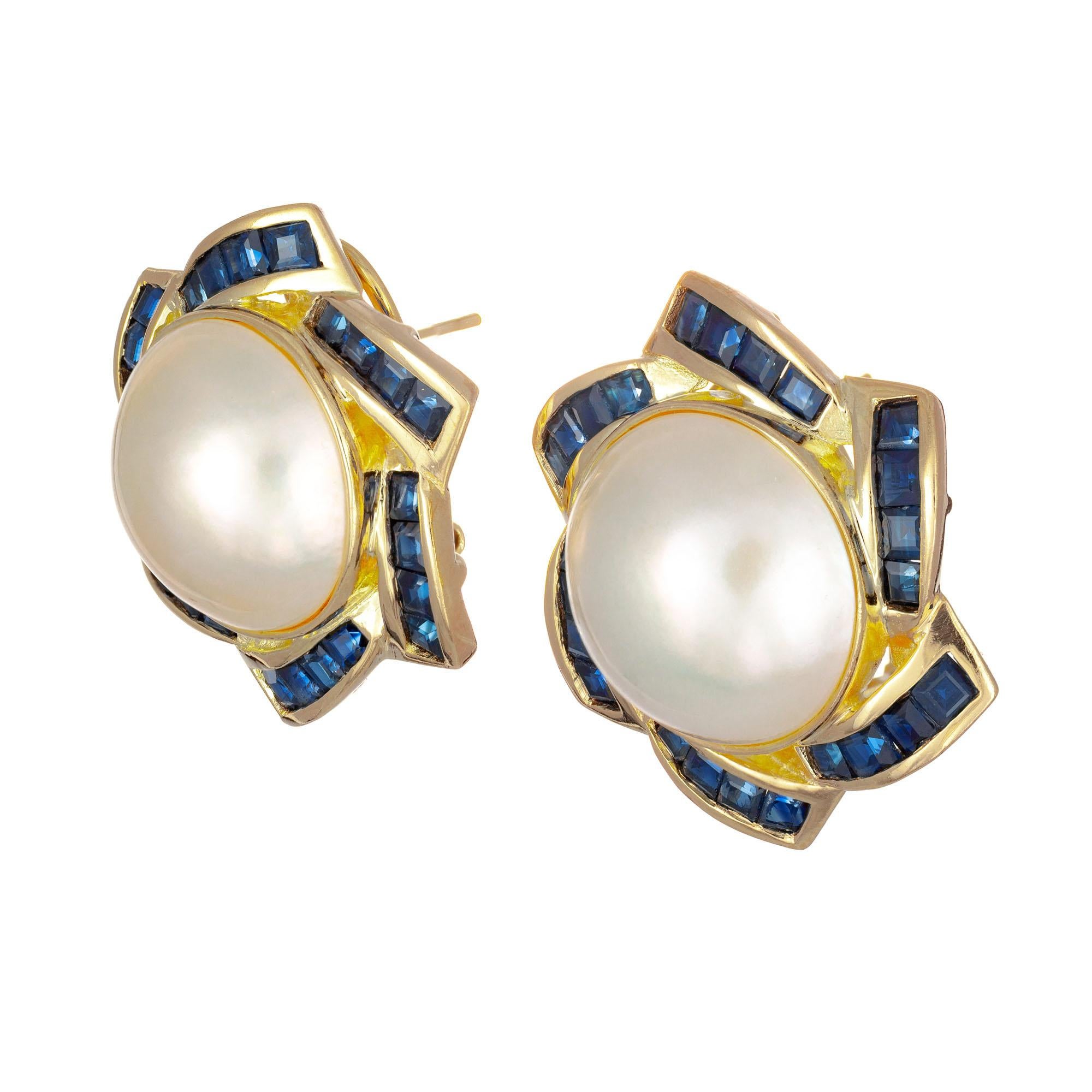 14mm Mabe pearl and sapphire clip post 14k yellow gold earrings. Circa 1990

2 Crème mabe pearls 14mm
48 square cut dark blue sapphires, approx. 2.00cts
14k yellow gold 
Stamped: 14k 585
12.8 grams
Top to bottom: 25mm or 1 Inch
Width: 24.7mm or