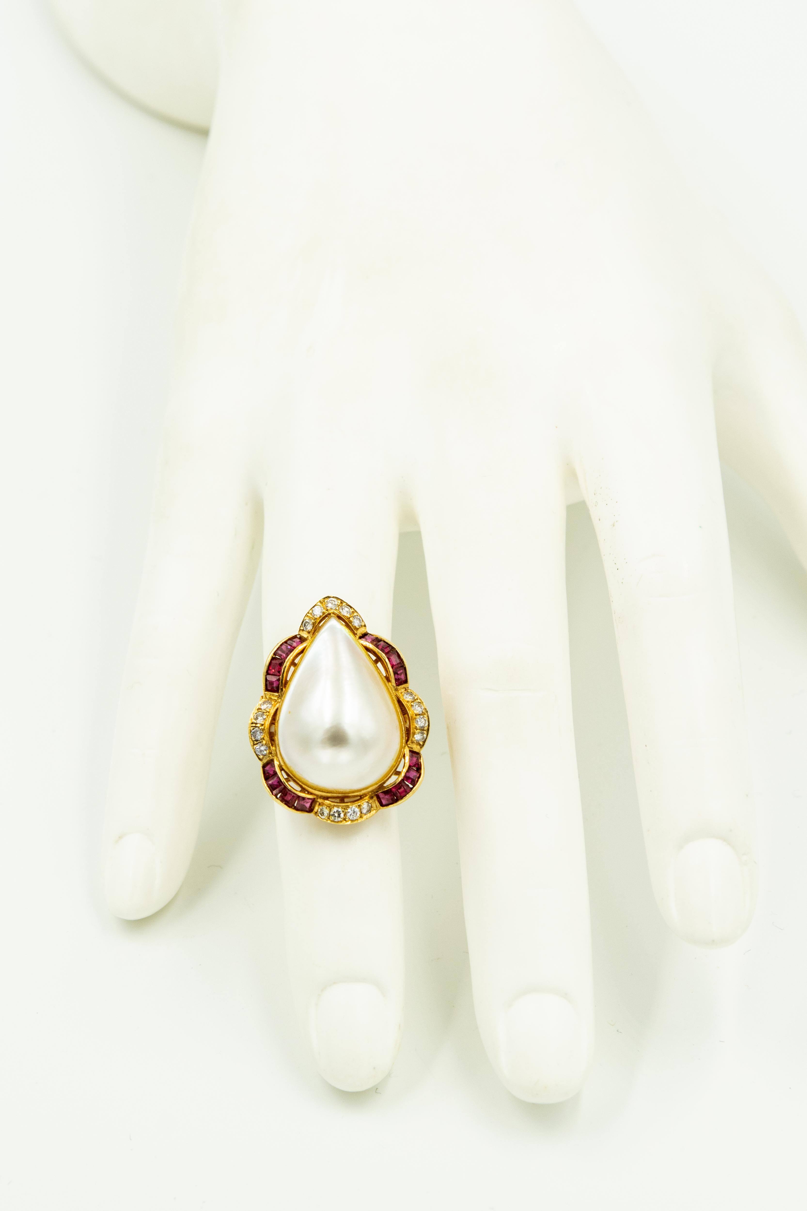 Elegant pear shaped mabe pearl centrally set in a scalloped diamond and channel set ruby frame that is mounted in 14k yellow gold suite containing:

A ring that measures 1.13