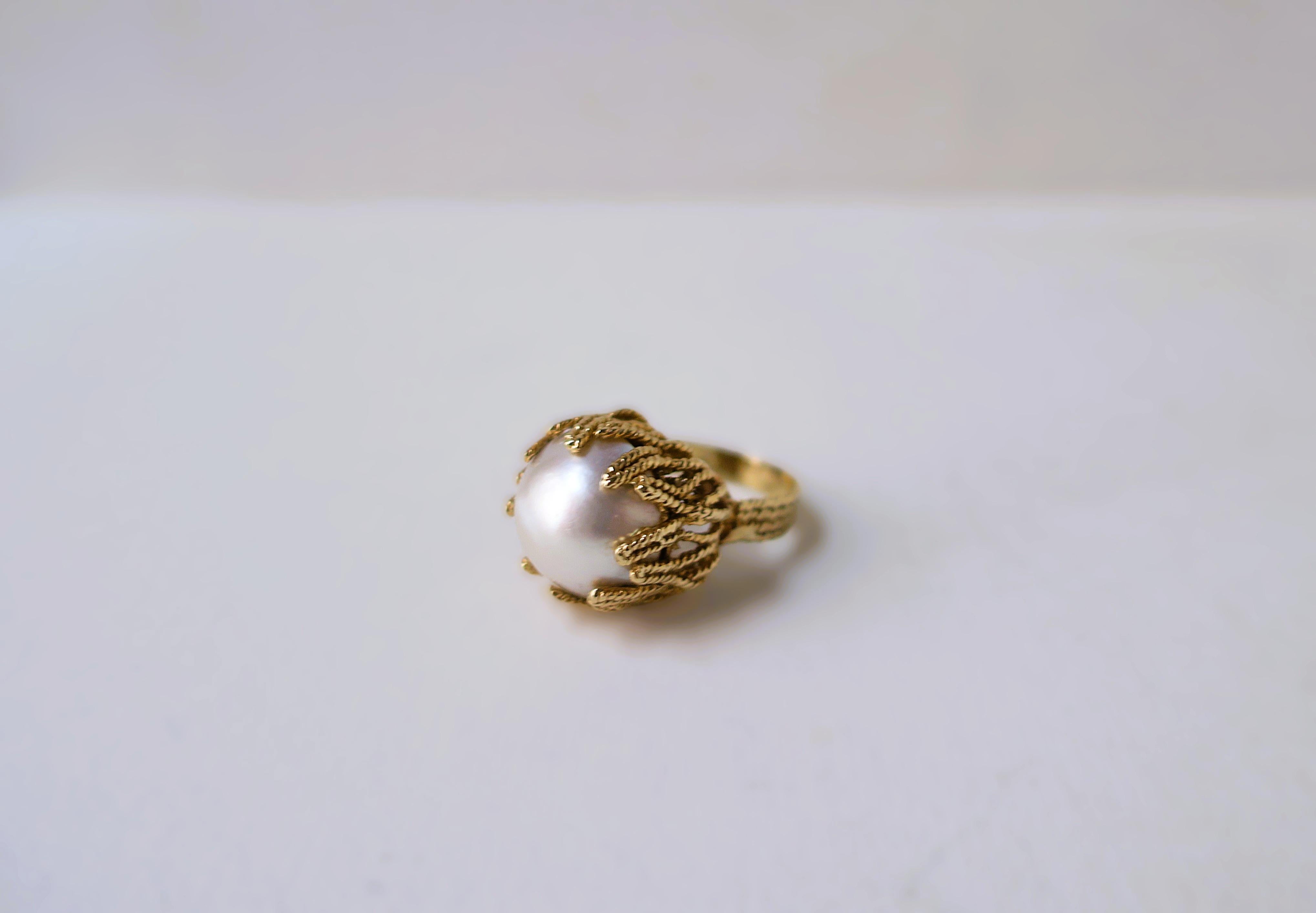Magnifique bague de cocktail en or et perles blanches de Mabe (ou Mobe), avec un motif torsadé en forme de corail embrassant la perle, vers le milieu du XXe siècle, années 1960. La bague est sertie d'or jaune 14 carats avec une perle de Mabe