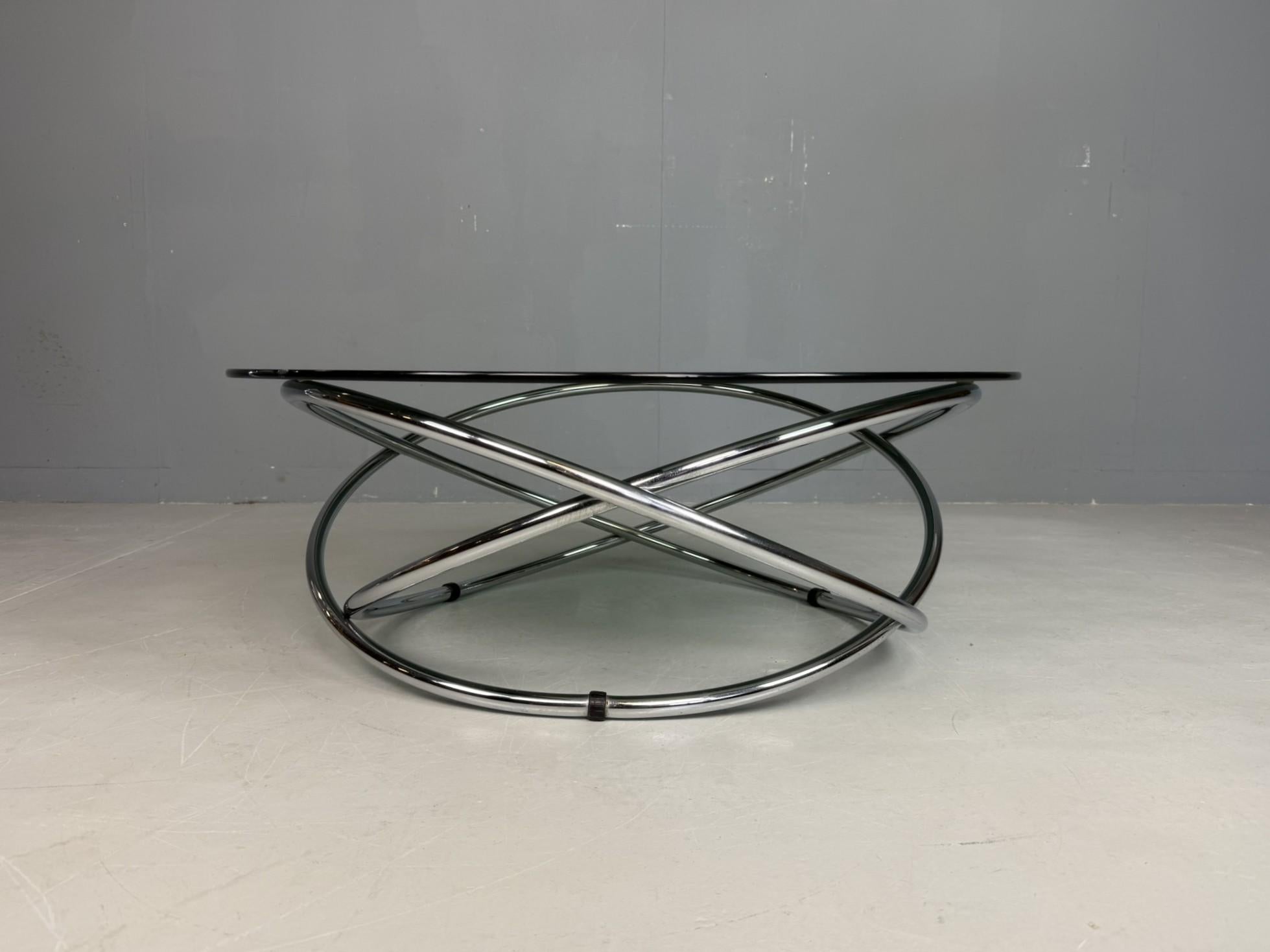 Avec la table basse MAC, Miniforms a transposé la fascination futuriste des années 1970 directement dans le design de meubles. Une structure atomique chromée audacieuse forme la base sculpturale, supportant un plateau rond en verre. À la fois