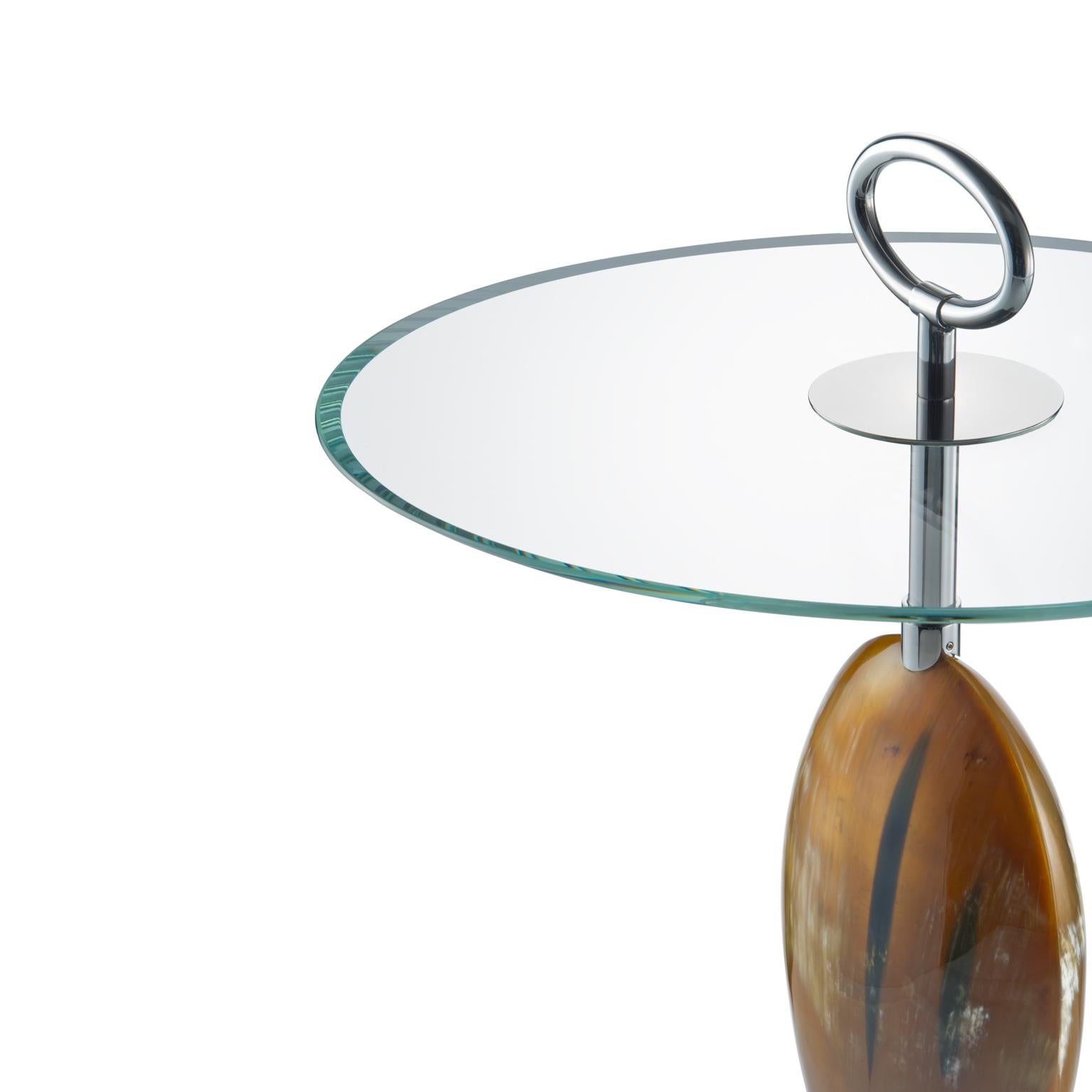 Exemple parfait d'un art impeccable, la table d'appoint Macari vous séduira dès le premier regard. Doté d'une structure élégante et d'une base en laiton chromé, ce design est rendu unique par une pièce décorative de forme ovale en Corno Italiano
