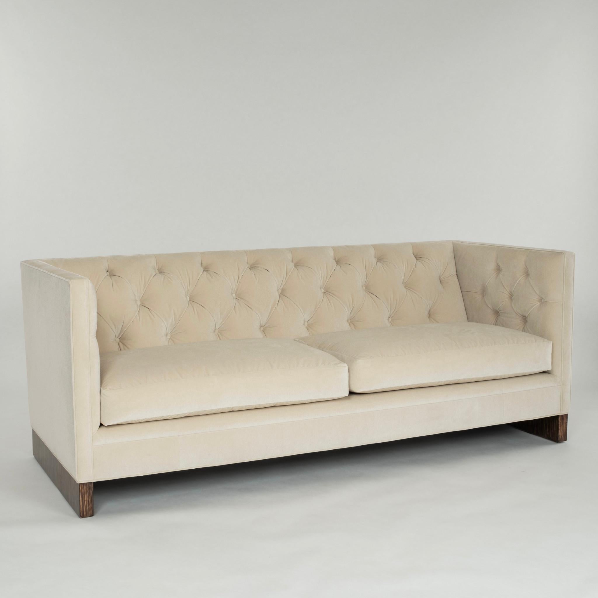 20th Century tuxedo sofa newly upholstered, featuring beige ecru performance fabric,  button tufting, feather down wrapped spring coil seat cushions, supported by Macassar Ebony wood.