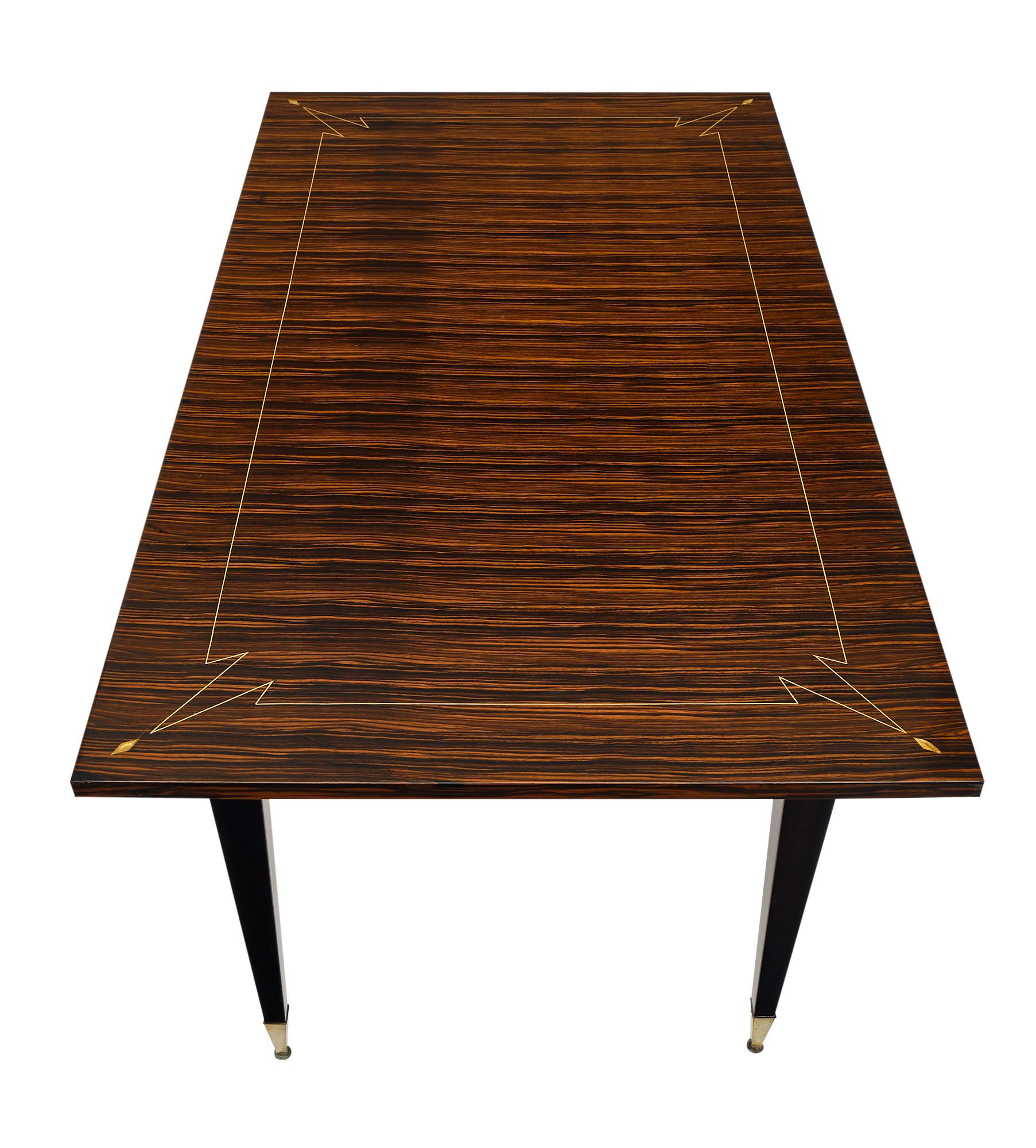 Dining room table from France made of Macassar veneer with mother of pearl inlays. This piece is supported by tapered legs with brass feet.