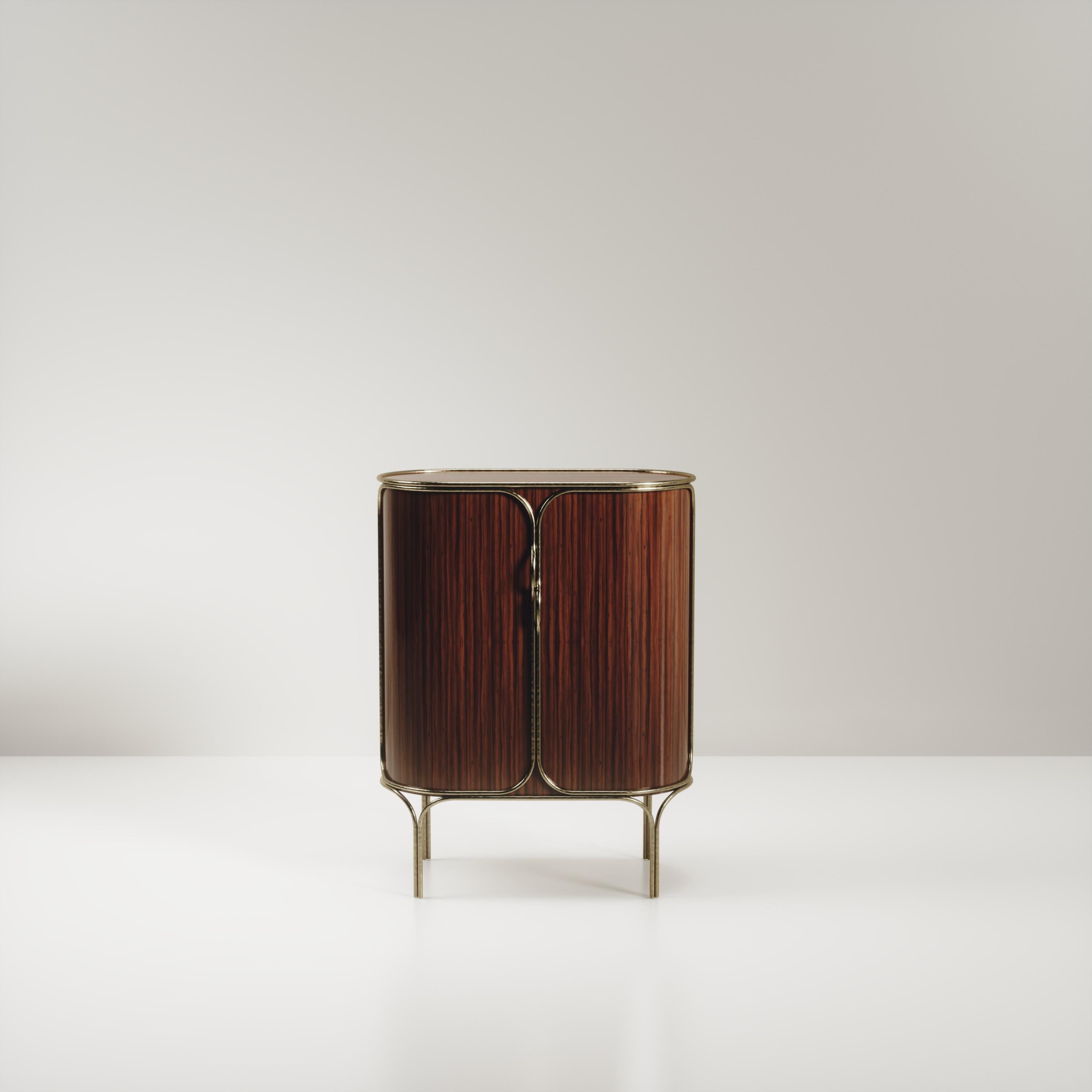 Le meuble bar Arianne de R&Y Augousti est une pièce unique. L'ensemble de la pièce est incrusté de bois de Macassar, accentué par des détails complexes en laiton bronze-patine qui ont l'effet 