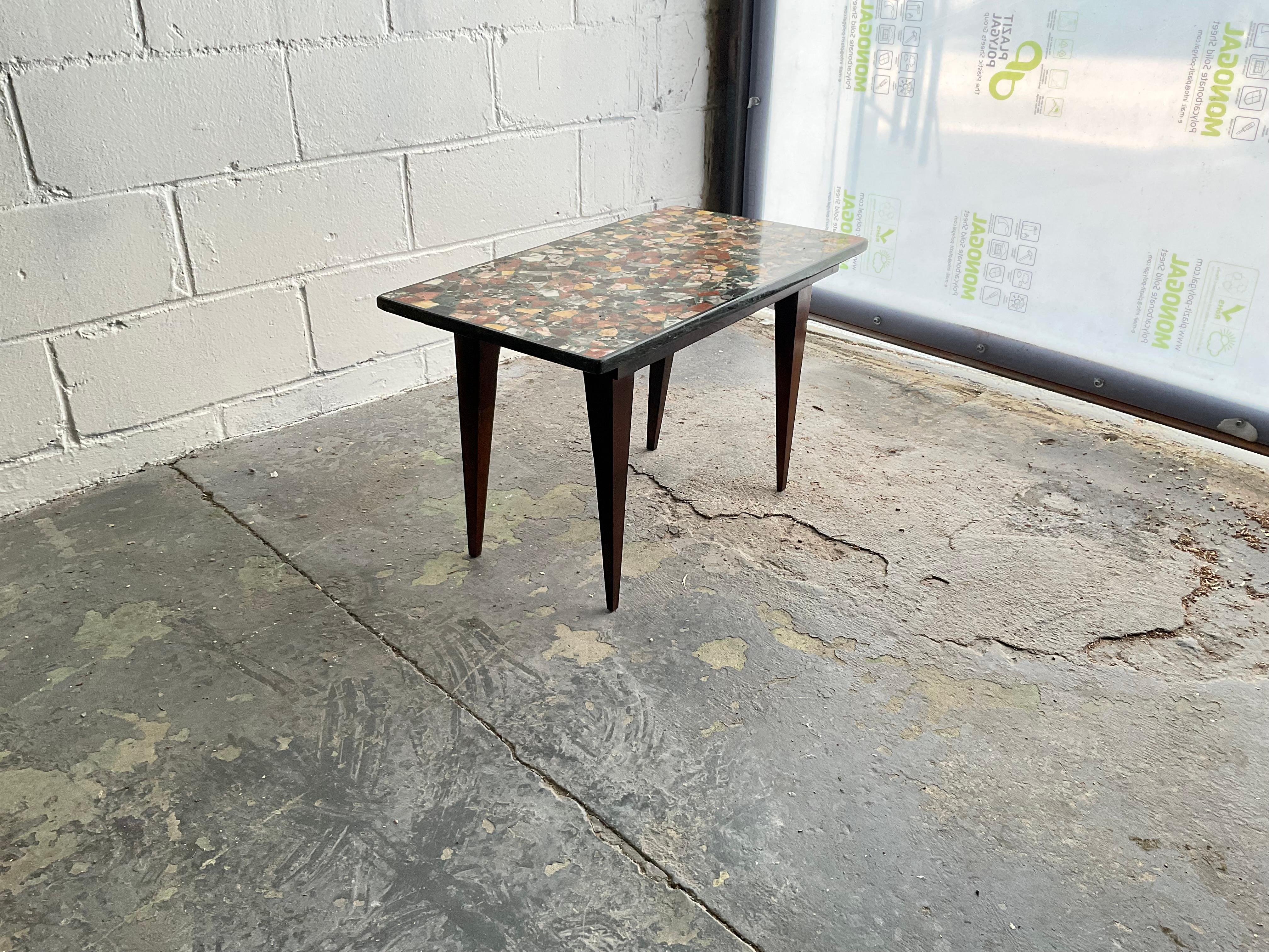 This is a unique table with an asymmetrical walnut base design of four straight tapered legs, crowned by a dynamic mixed stone terrazzo top. The base for this design was inspired by the furniture of Mario Bellini, a giant of 20th century design who