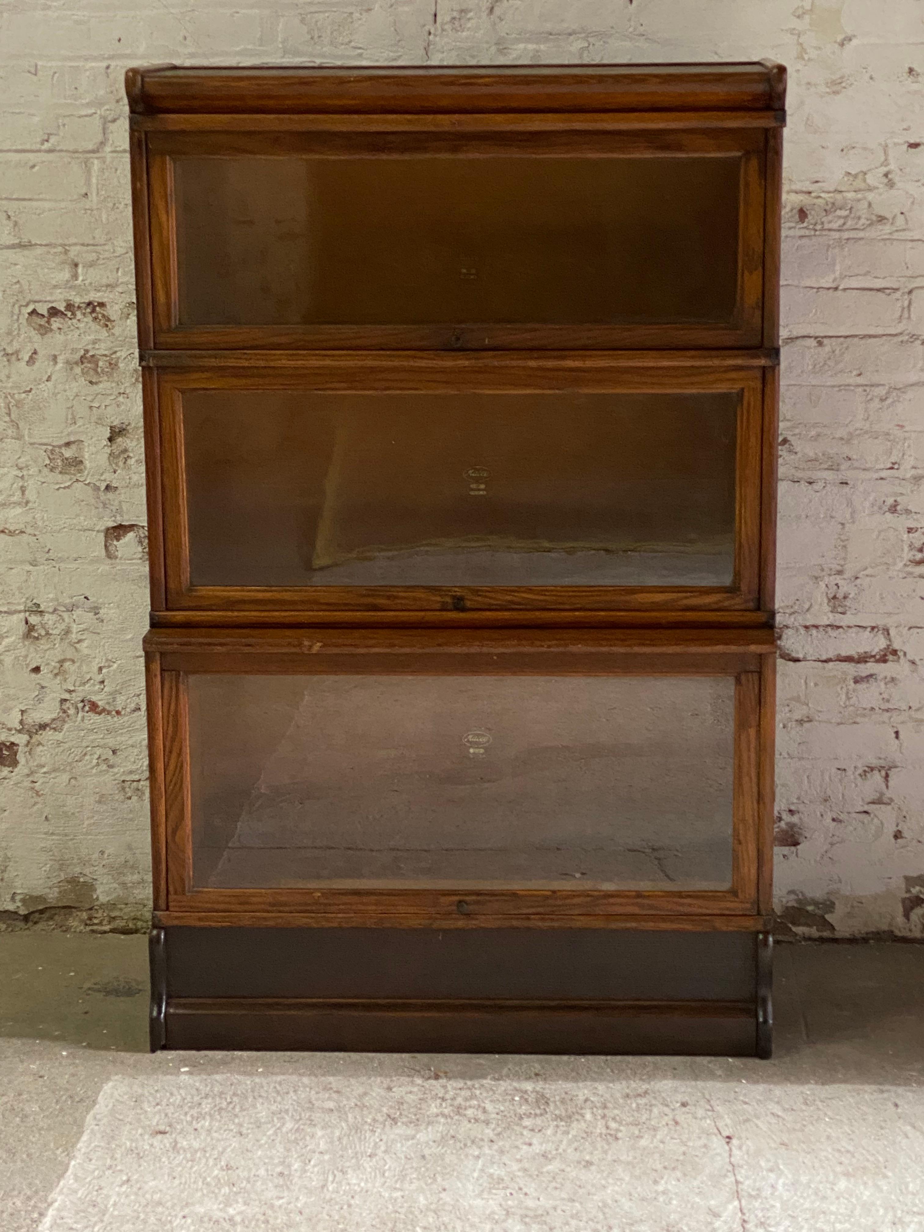 Macey three stack barrister bookcase with copper flashed japanned hardware. Three stack compartments with a base and top. Original dark finish, circa 1910-1920. The bottom component is the largest with interior measurements approximately 12.5