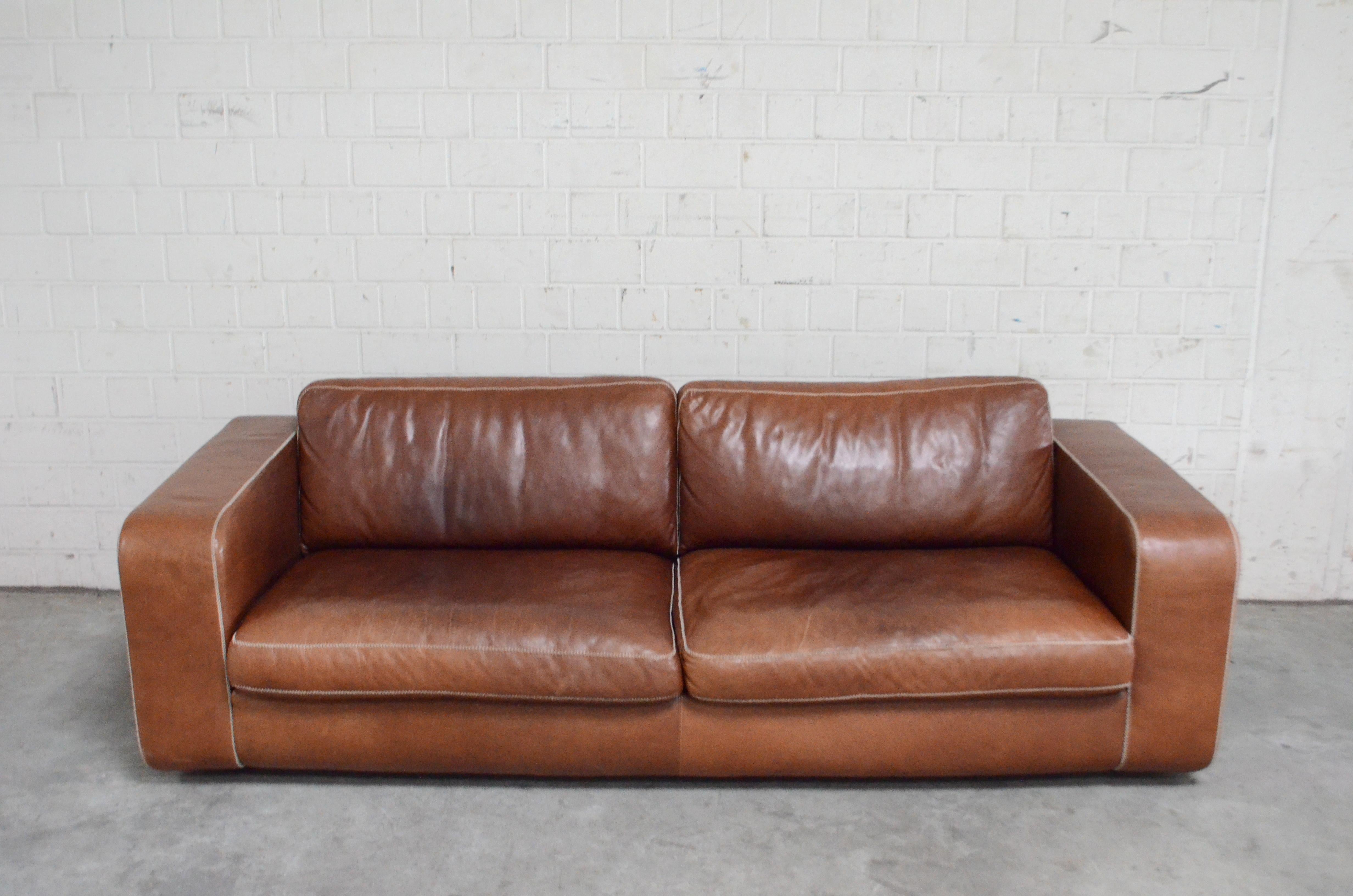 Machalke leather sofa in cognac aniline leather and white cross seam stitches.
Model Valentino.
Design Michael Schilte.
Great patina.
Machalke is a German furniture company with manufactures high quality craftmanship leather seating furniture as