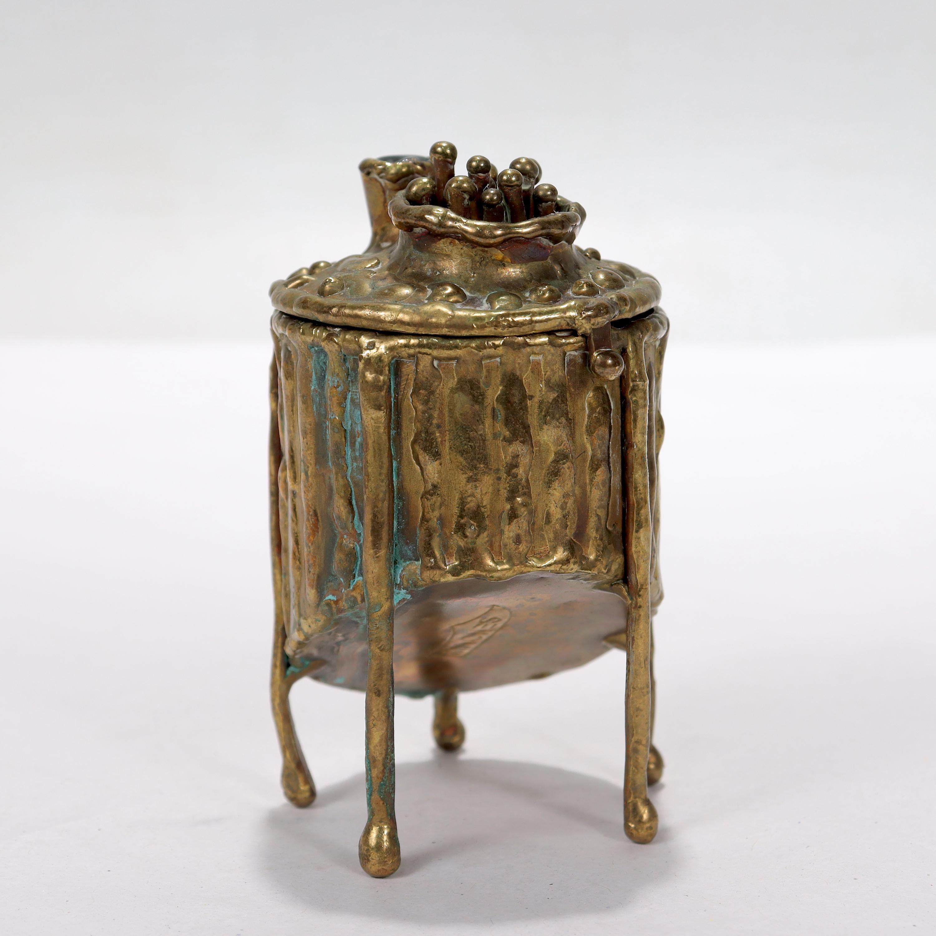 A fine Brutalist dresser box.

With embossed lines around the circumference and a slanted body.

In the style of Pal Kepenyes.

The lid is decorated with a bowl-like shape containing 10 small poles terminating in balls, and a cup-like shape with a