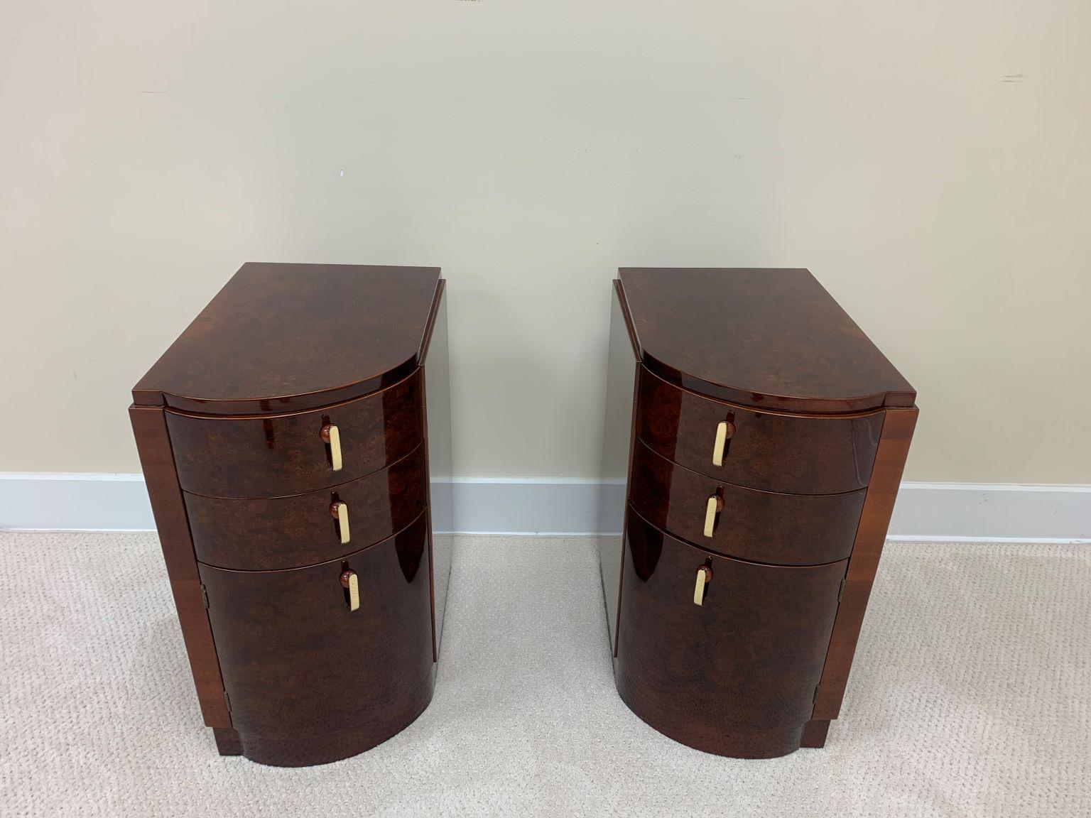 Machine Age Art Deco burl and brass night tables circa 1930s. Beautiful and functional set of left and right tables. These gorgeous burl and mahogany woods are accented by solid brass and Bakelite handles. With two drawers and a door these tables