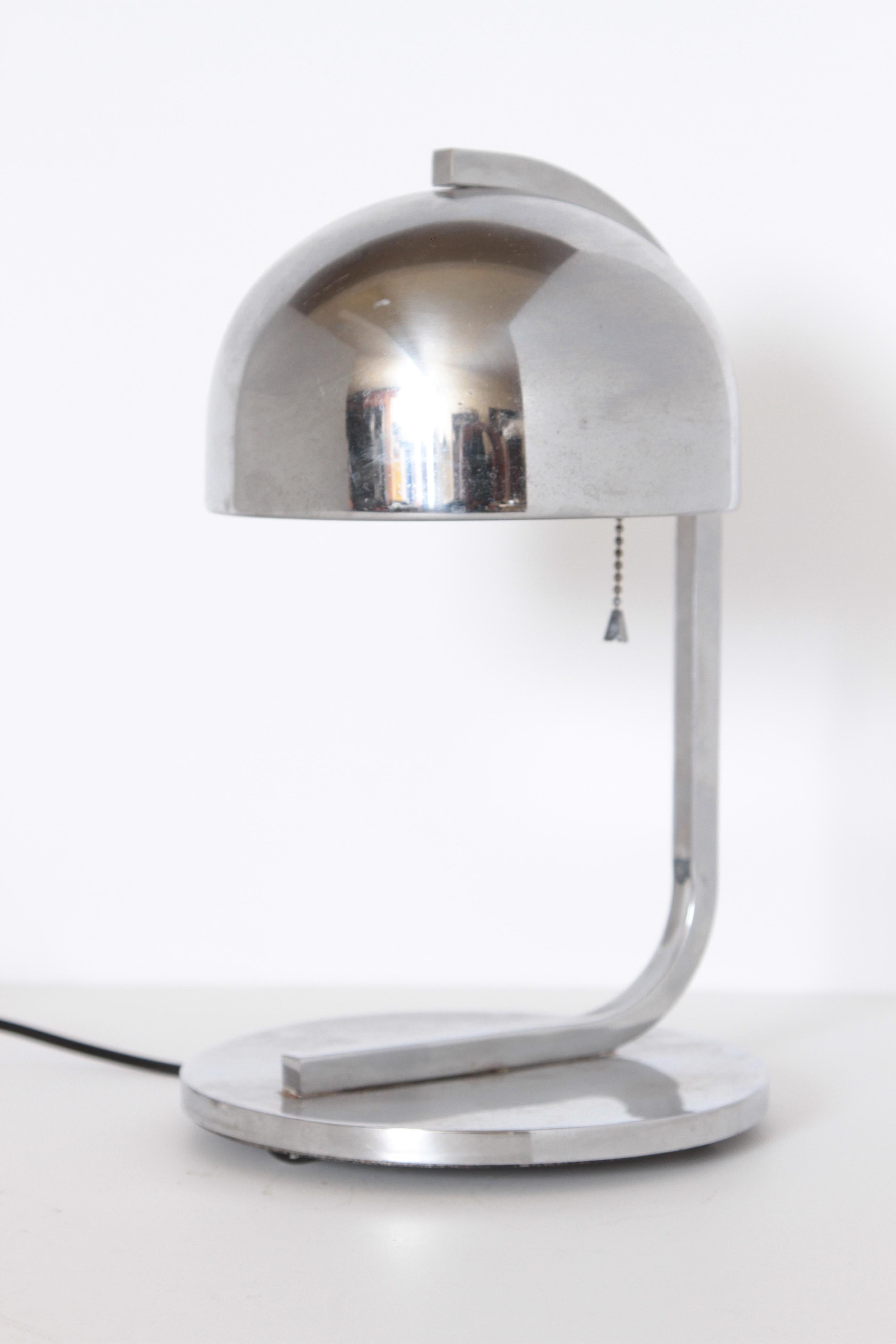 Machine Age Art Deco Streamline chrome table lamp in the manner of Donald Deskey

Square-tube arm with bell-shaped shade, a la Deskey / Nessen, with under-weighted circular base.
A well-constructed Industrial design example.
Normal wear from