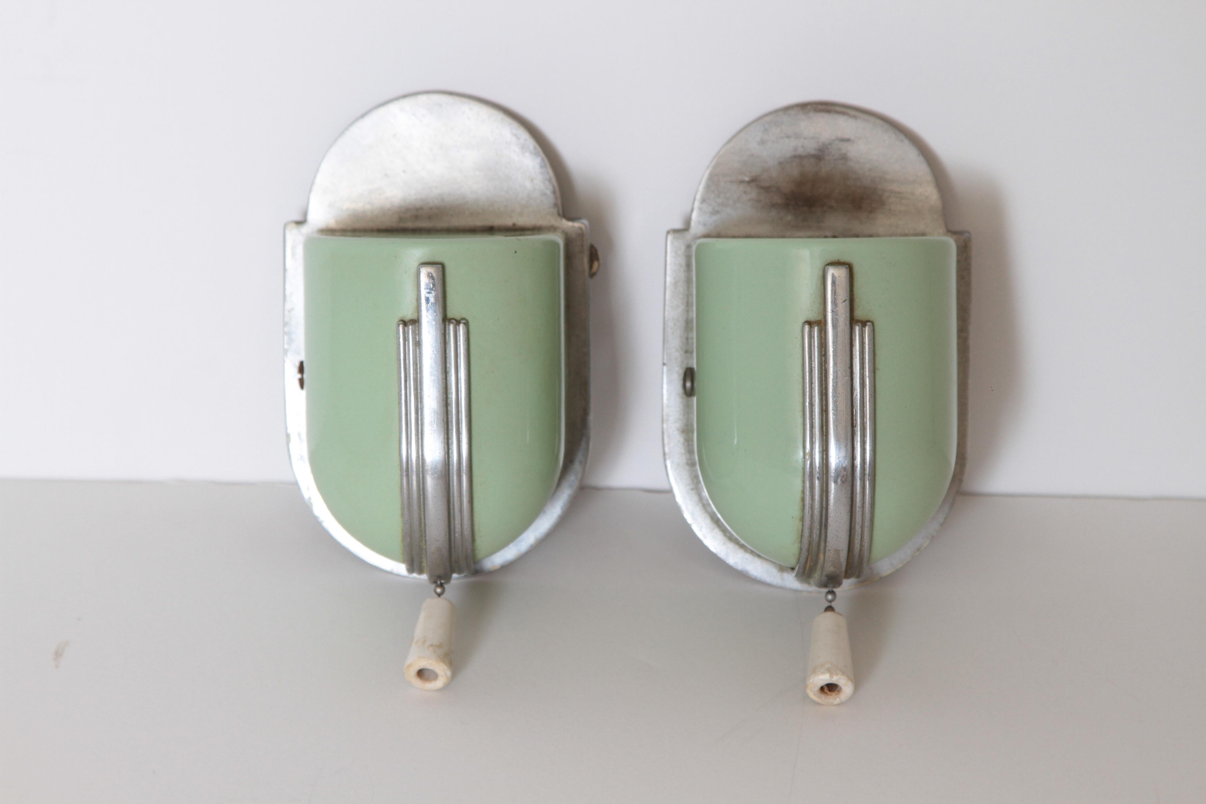 Machine Age Art Deco streamline wall fixtures bathroom sconces

1930s vintage all-metal construction; chromed cast-metal mount-plate, mint-green enameled metal body, with chromed speed-stripe adornment and original ivory colored ceramic pull-chain