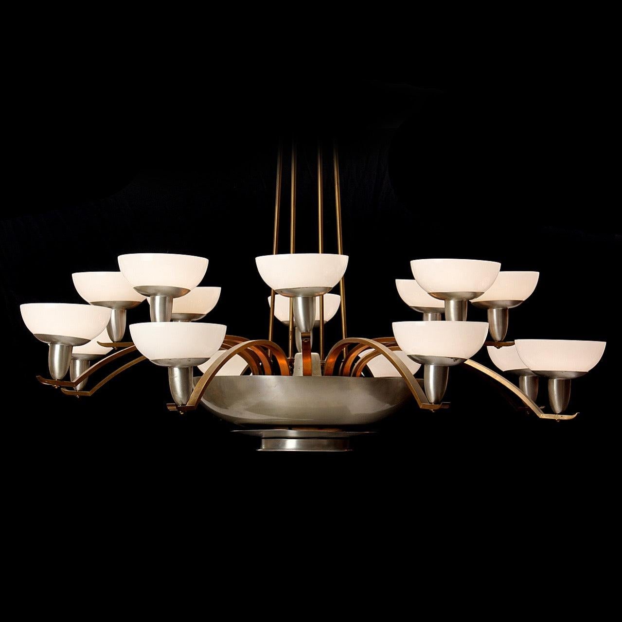 A dramatic and well-scaled brass and aluminum chandelier with sixteen up lit lamps and a central down lit lamp.