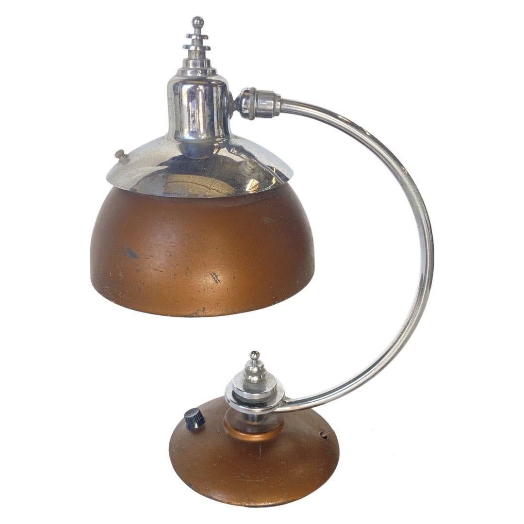Machine Age, Art Deco Copper, and Chrome Desk Lamp from 1932. The lamp features a modernist bell-shaped copper lamp shade with a matching copper base all brought together with a chrome Streamline Moderne curved steam and stepped finial along the