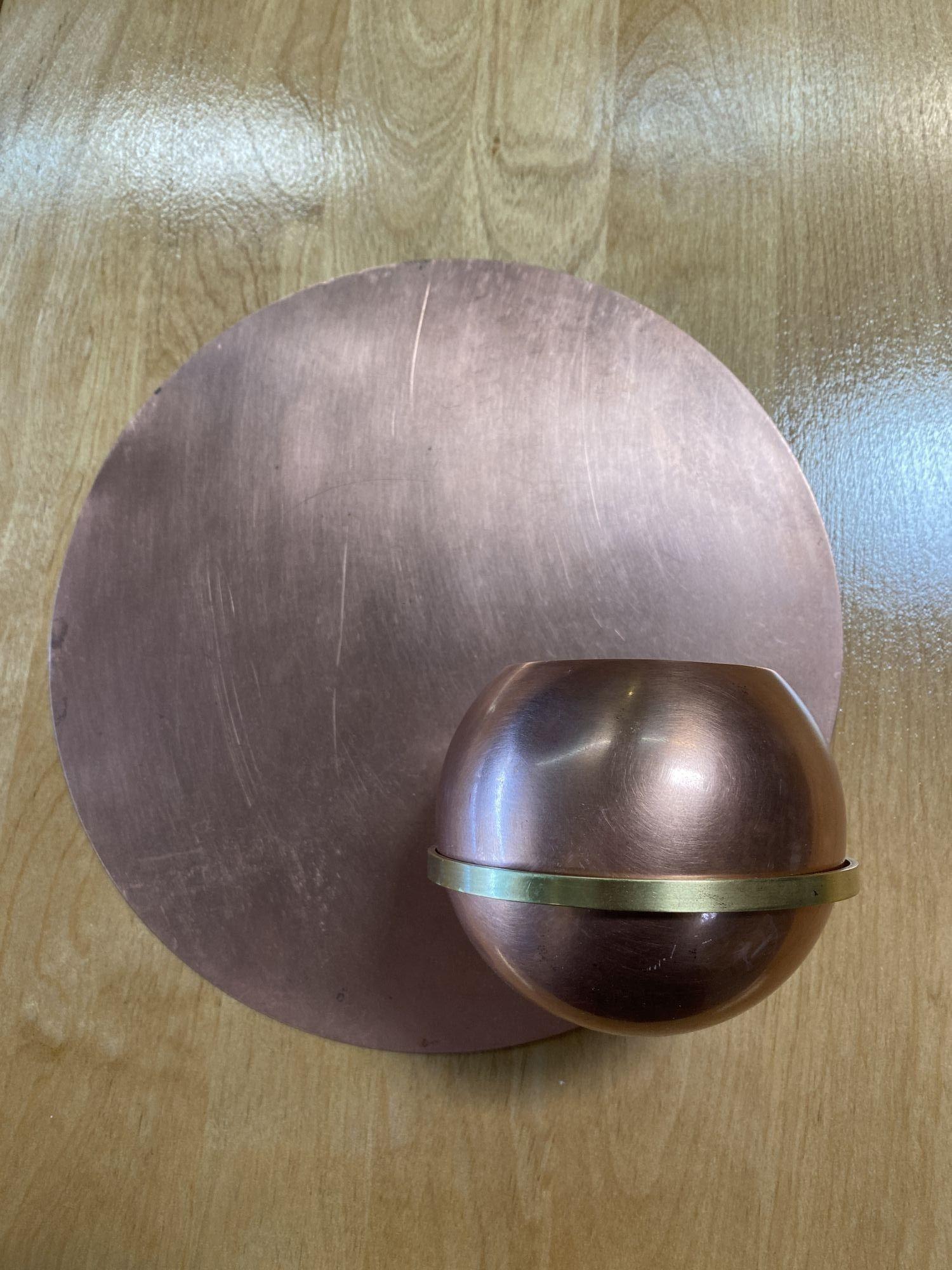 A unique pair of Art Deco wall planters crafted from copper and brass. This exceptional set includes two wall platters, each mirroring the other, presenting a round copper backplate, a brass ring-shaped holder, and a removable sphere-shaped planter.