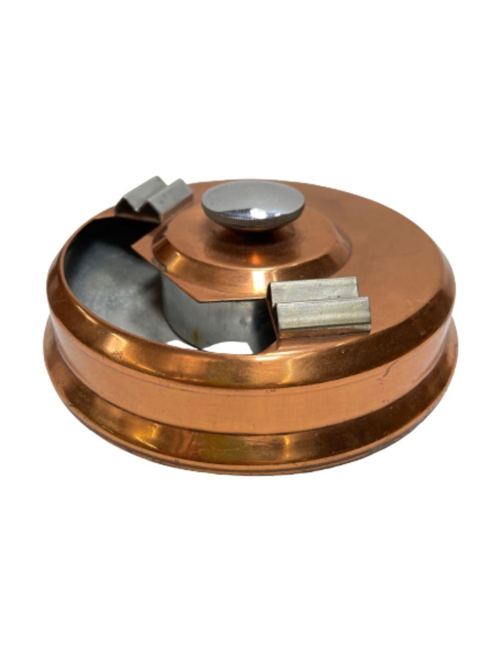 Machine Age Copper and Steel Smokeless Ashtray featuring streamline styling with geometric accents. The ashtray features a solid copper construction with a polish steel interior with 2 steel cigarette holders on each side of the opening. The center