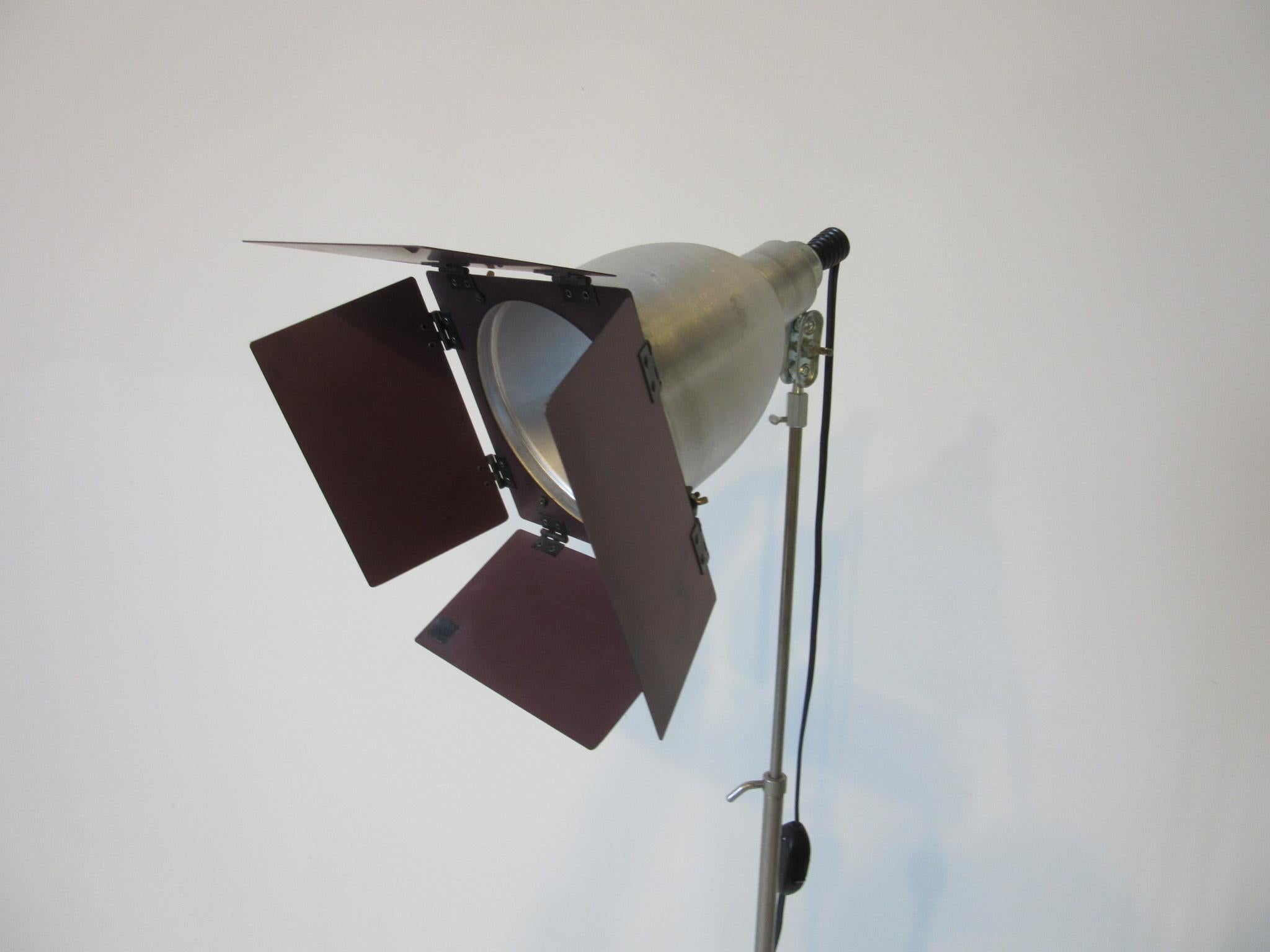 A Machine Age Art Deco styled Industrial floor lamp with folding anodized metal shades to the lamp head in brushed aluminum with steel tri - folding legs. Has a adjustable head and shaft manufactured by the Smith - Victor Company. Great floor lamp
