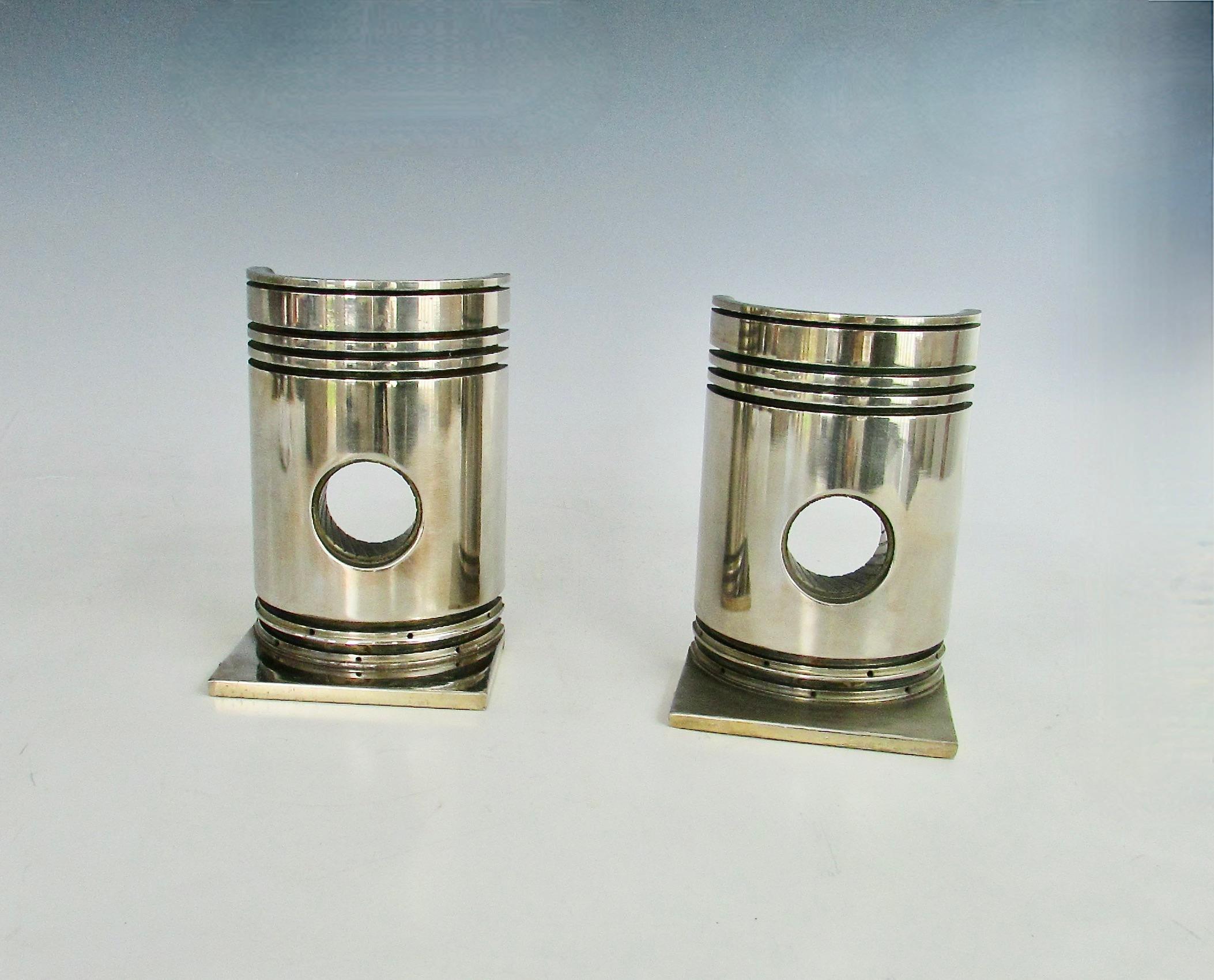 Pair of bookends fashioned from a large internal combustion engine . Assembled in a machine shop or aboard a ship . Piston cut in half . Attached to quarter inch thick base them nickel plated . . Nice substantial pair with some weight . Great for