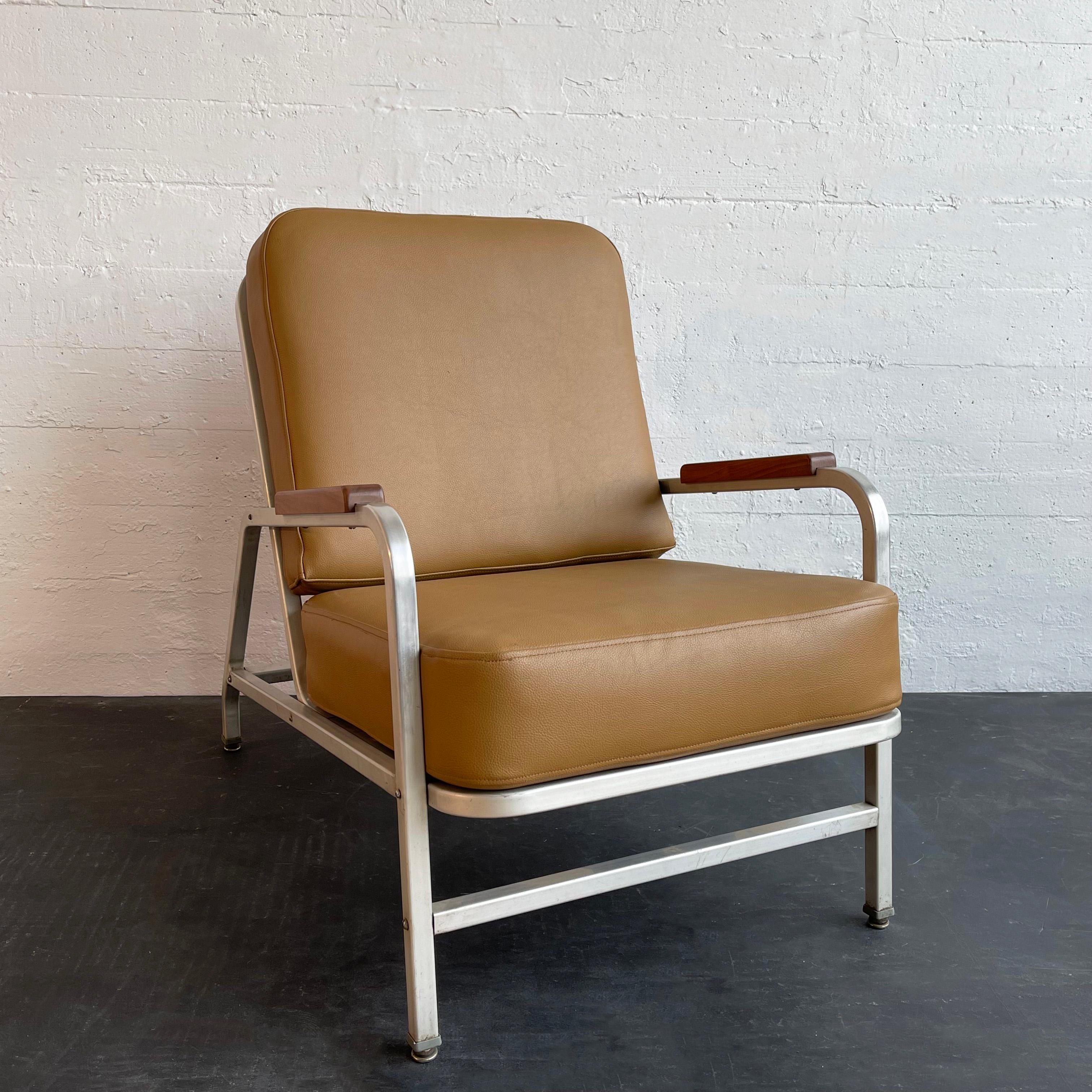 Machine-age, mid-century, lounge armchair circa 1940's features a sleek, light weight, aluminum frame with maple armrests and newly upholstered seat and back cushions in camel tan textured vinyl. 