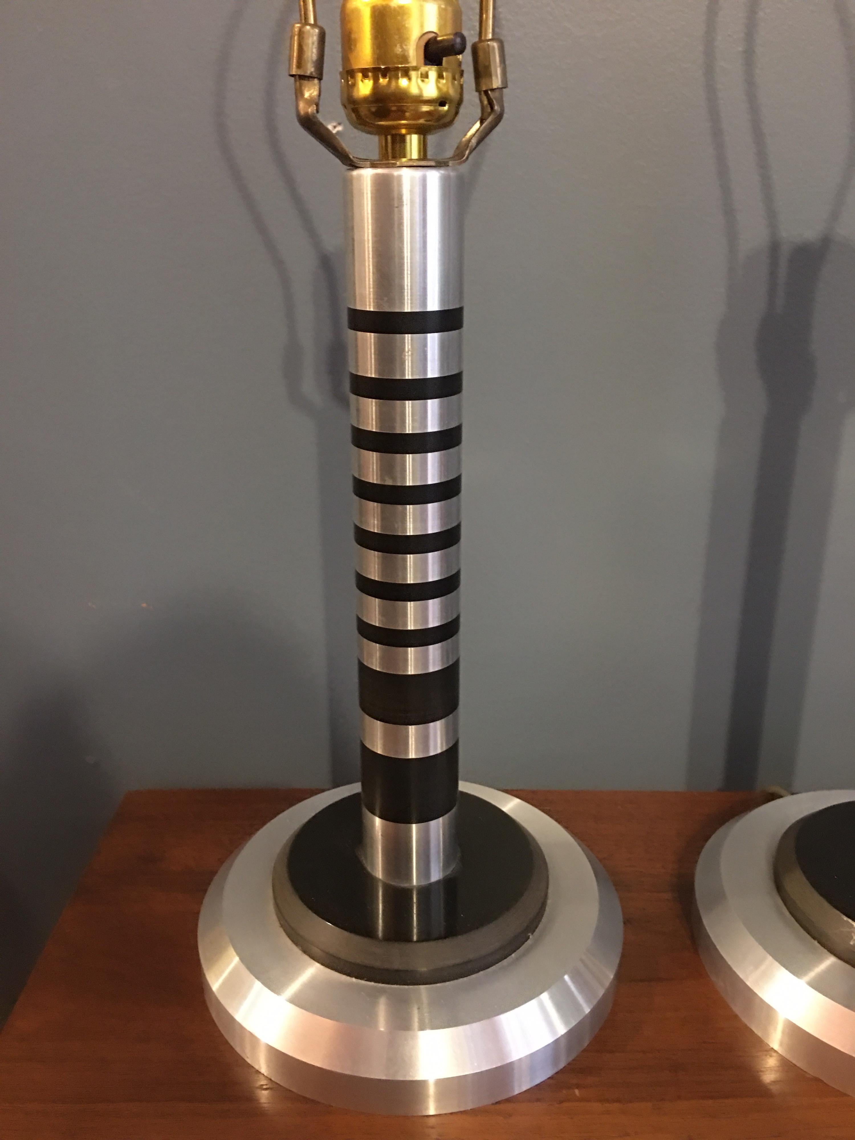 Machine Age pair of aluminum table lamps. Most likely from the 1980s in the style of Walter Von Nessen/ Pattyn products 1930s aluminum lamps of the period. Stacked columns made up of aluminum and possibly ebony like material? Lamps are in really