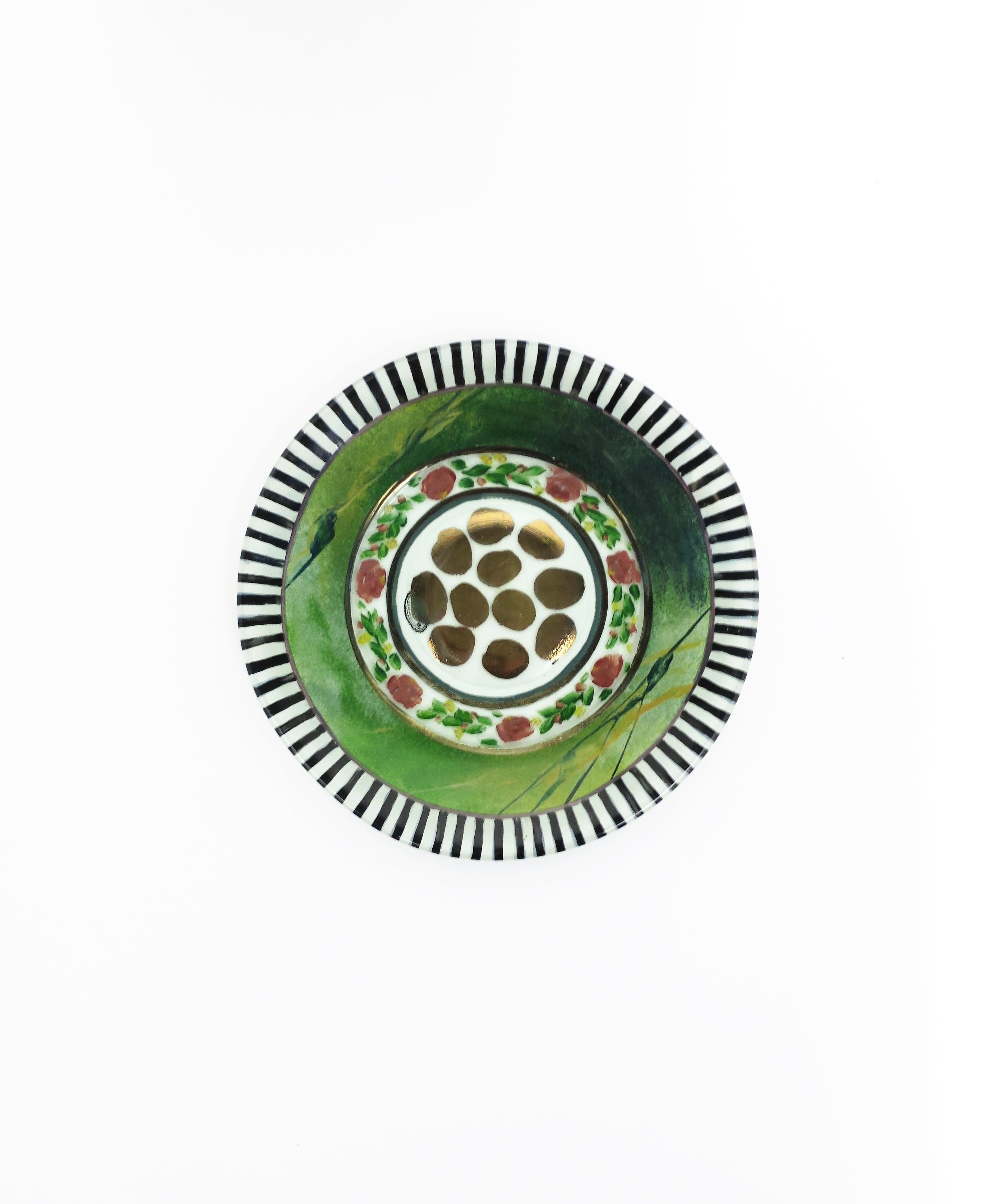 A beautiful authentic designer plate or dish by designers' MacKenzie-Childs, circa 1990s, New York. A rare piece, hand-painted plate with a black and white boarder edge, Kelly green and floral circular design, and gold animal-like spots at center.