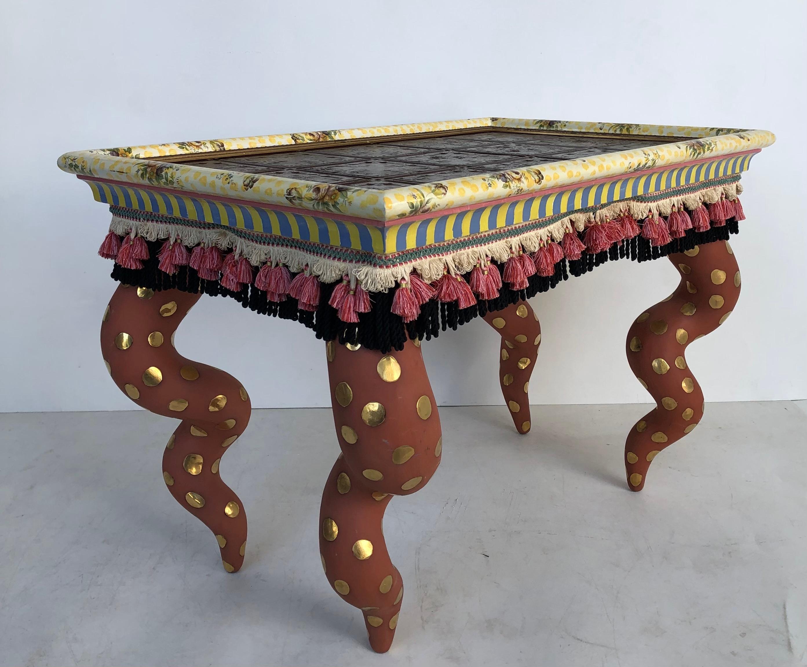 Mackenzie Childs painted ceramic/wood coffee table with tiles, tassels, signed

Offered is a Victoria & Richard Mackenzie Childs ceramic and wood coffee table. The top is inset with glazed tiles. The hand-painted coffee table is decorated with