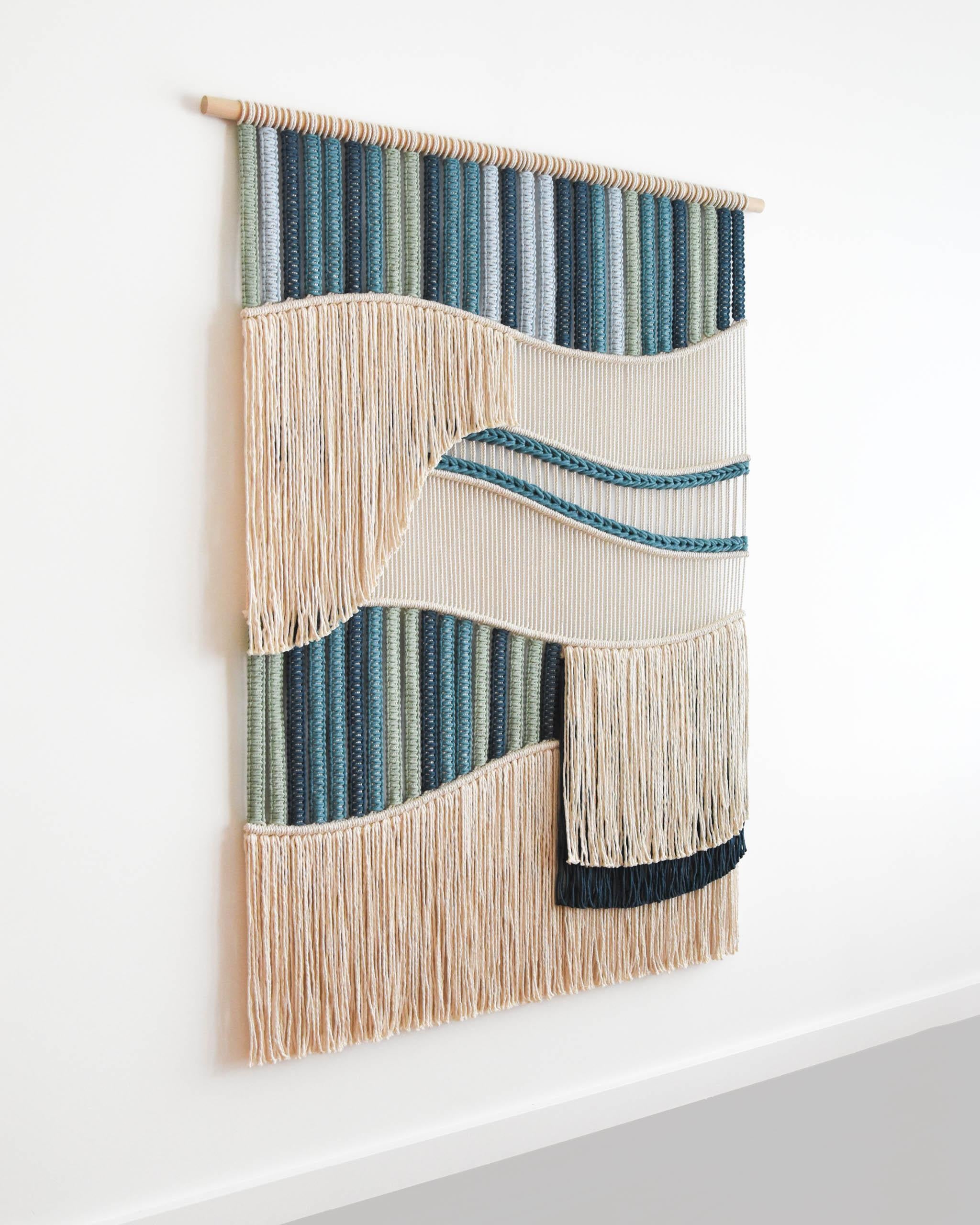 FLOW è un arazzo di fiber art realizzato con centinaia di nodi, una tecnica nota anche come macrame.
Il design è un'esplorazione della forma e della consistenza, esaminando l'interazione tra linee fluide e sezioni stratificate per ottenere un'opera