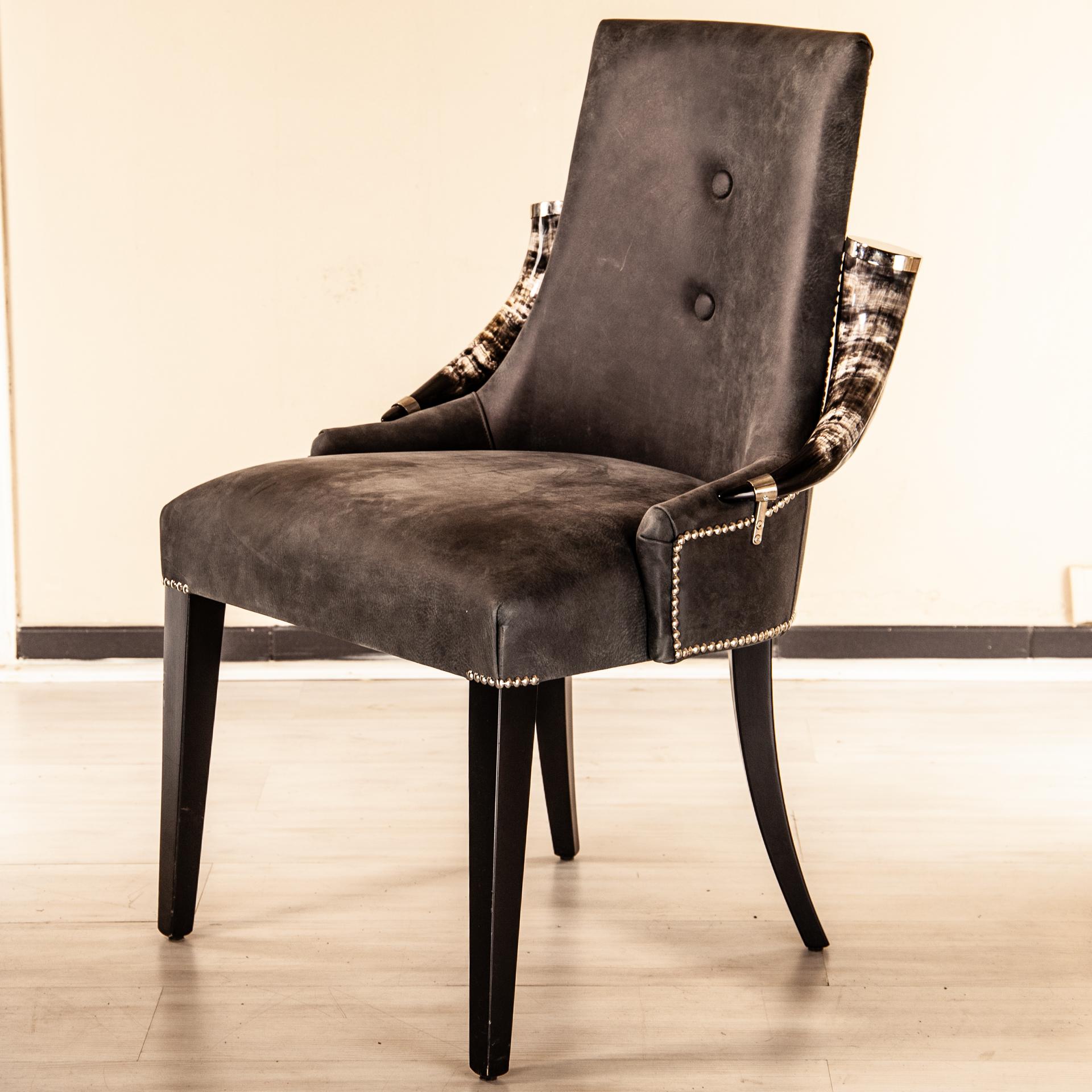 Madagascar armchair with two American Horn arm-rest that are finished with brass element caps and connection element to the frame.
Here shown with a primo fiore Tuscan antique gray taupe leather. Upholsterer nails to close and stretch the