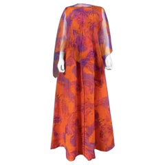 Abito haute couture di Madame Grès degli anni ’70, in chiffon arancione a fantasia floreale con mantella
