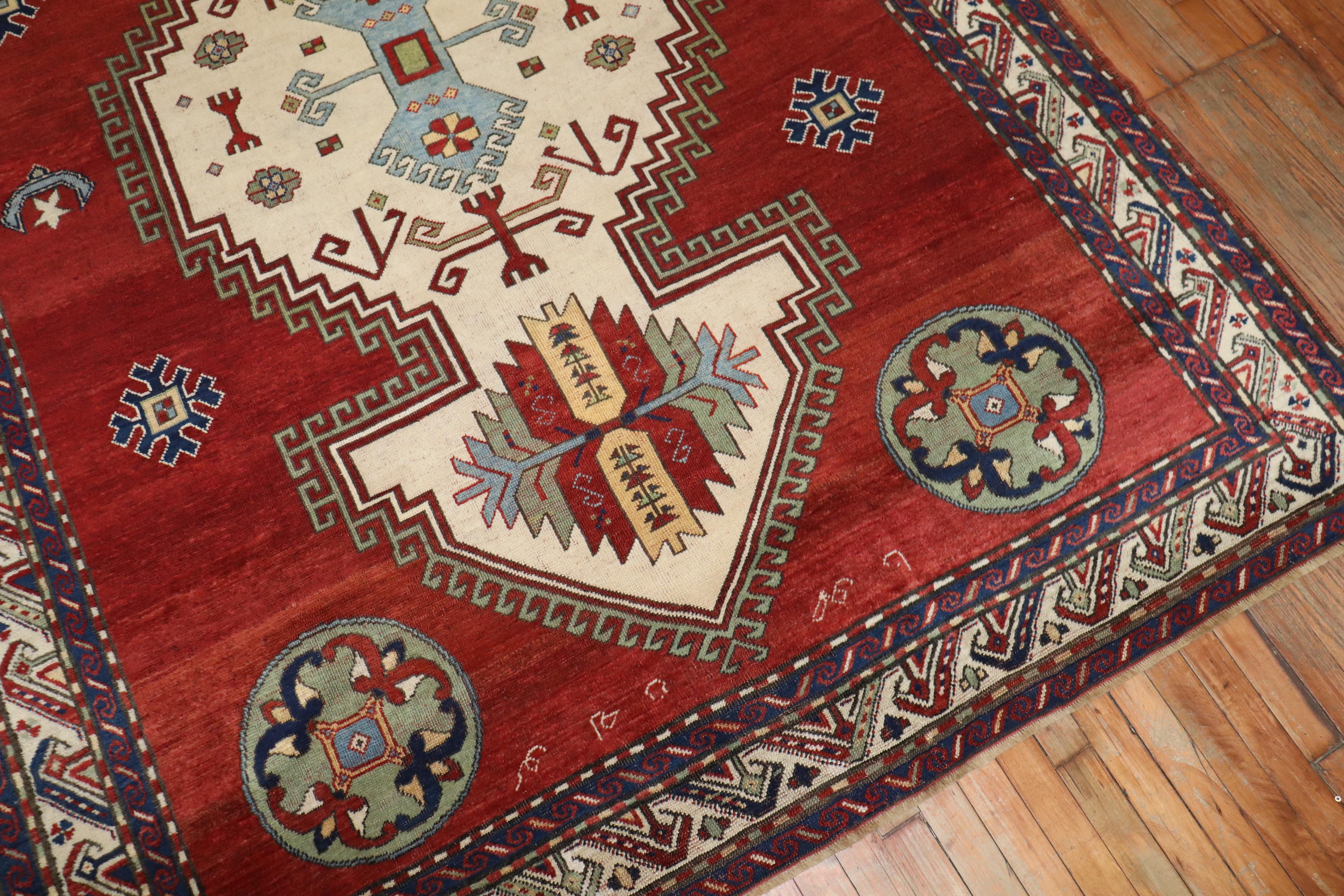 A geometric tribal-looking Armenian Kazak rug dated 1940. Some Armenian writing can be seen in the detailed shots as well. Some olive green, navy soft blue accents as well. The medallion is ivory

Measures: 6'5'' x 9'1''.

 