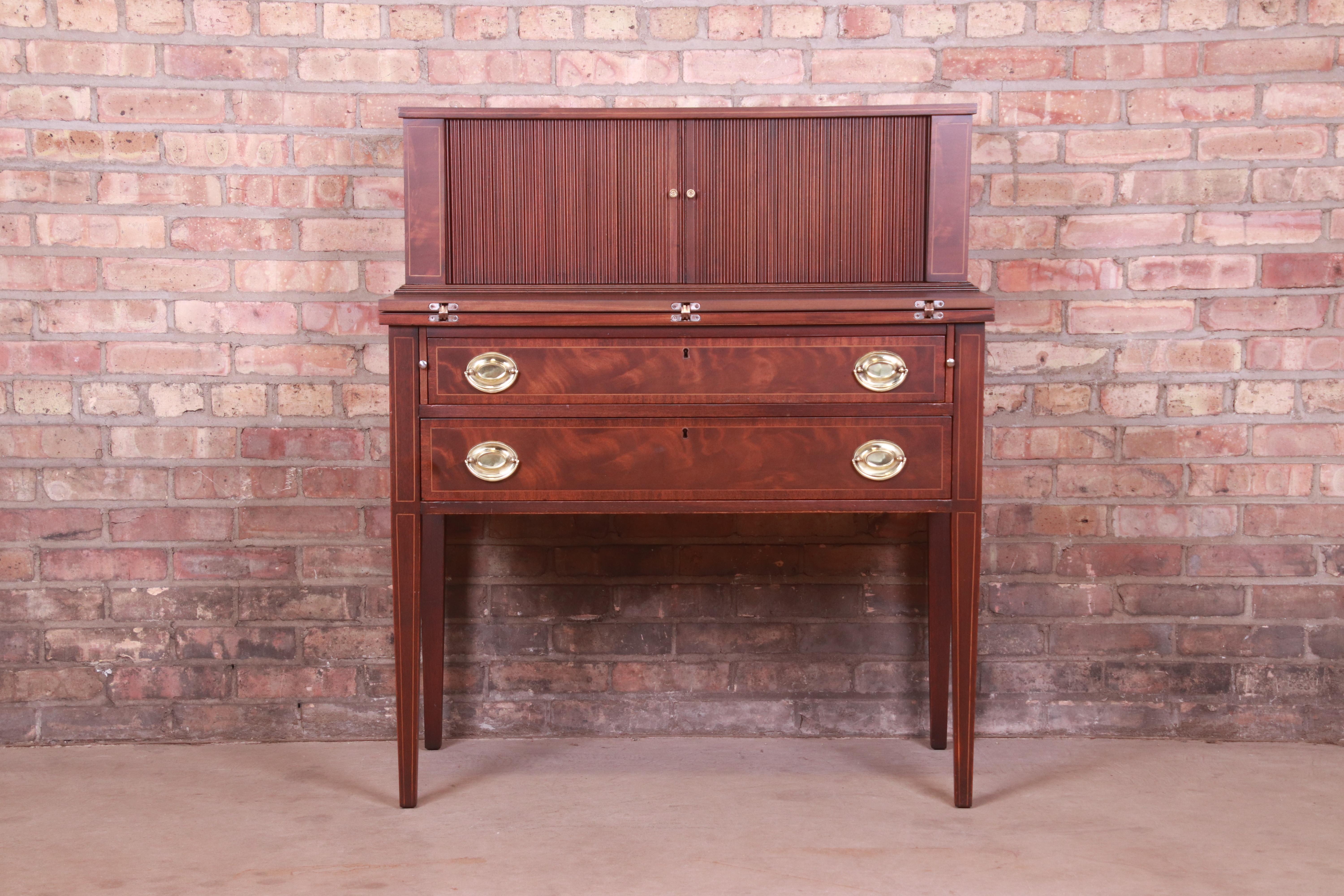 A gorgeous Hepplewhite or Federal style tambour door writing desk or secretary desk

By Maddox

USA, Circa 1940s

Flame mahogany, with satinwood string inlay and original brass hardware.

Measures: 36